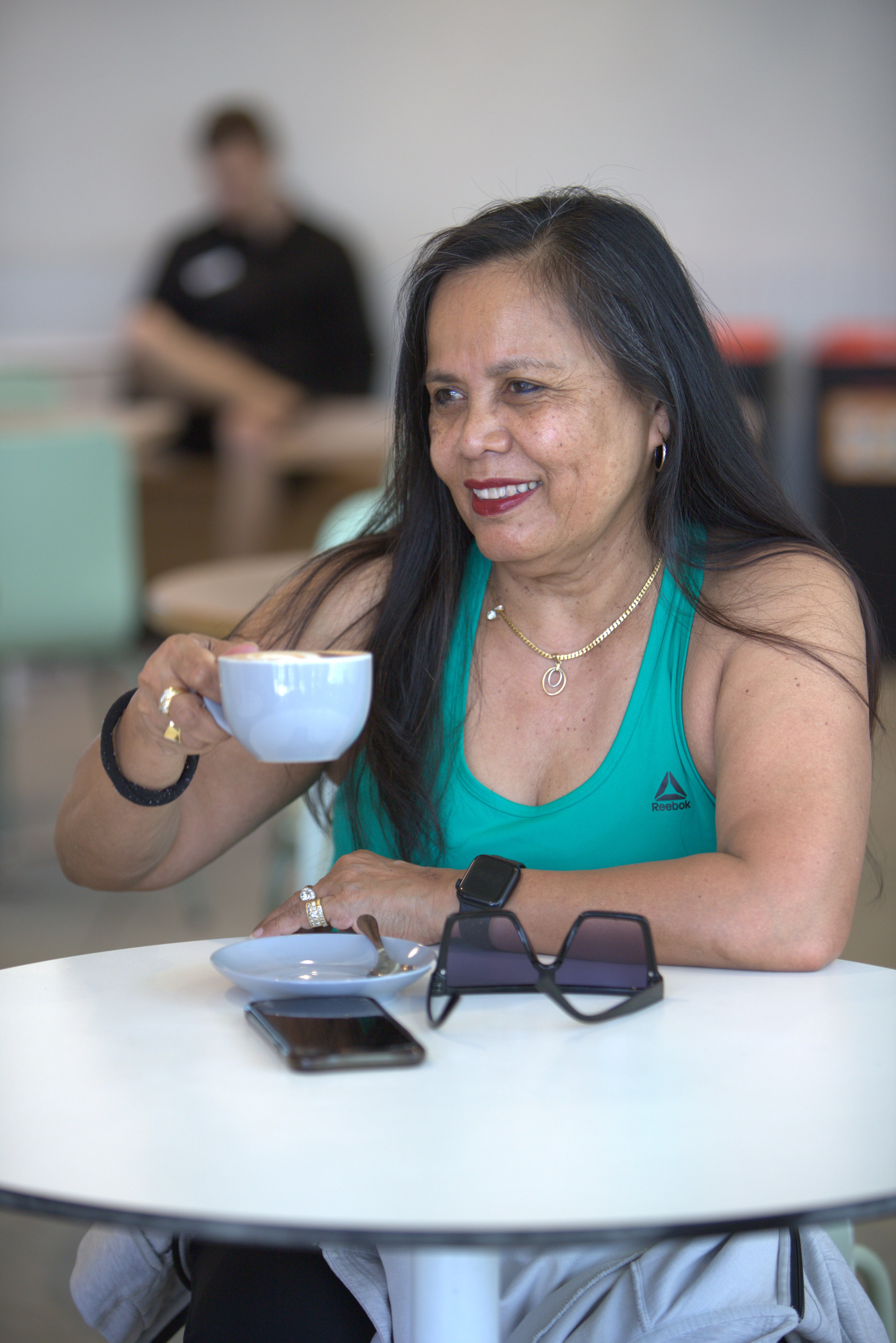 Wendy smiling and enjoying a cup of coffee at Gunyama Park cafe