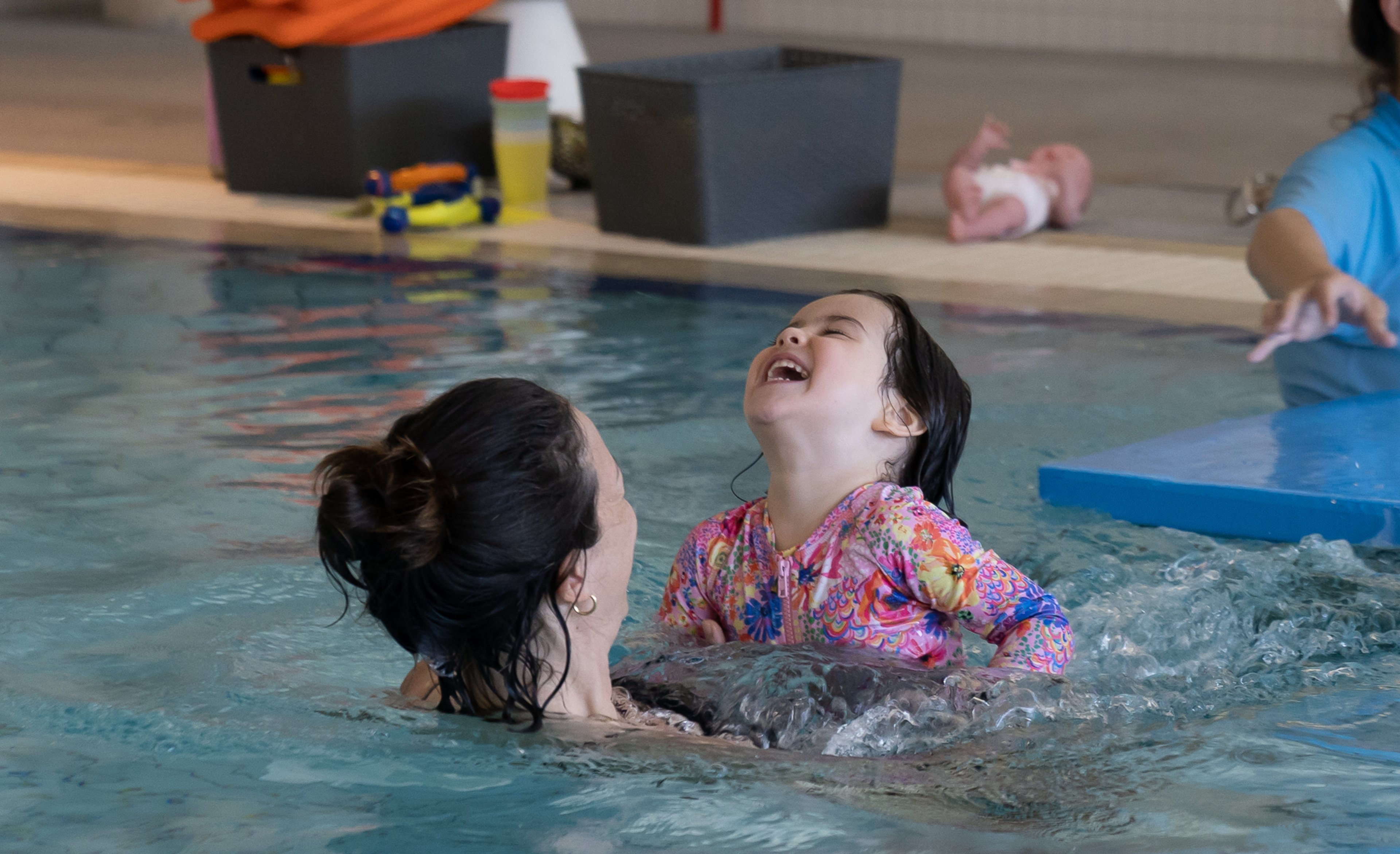 A young girl laughing with her mum in the pool at Gunyama Park 