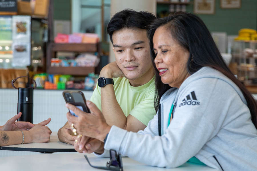 Man and woman sitting in Gunyama Park Cafe browsing a mobile phone