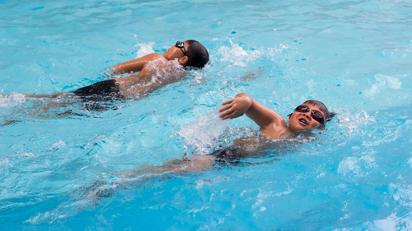 Two young boys doing freestyle laps in the pool
