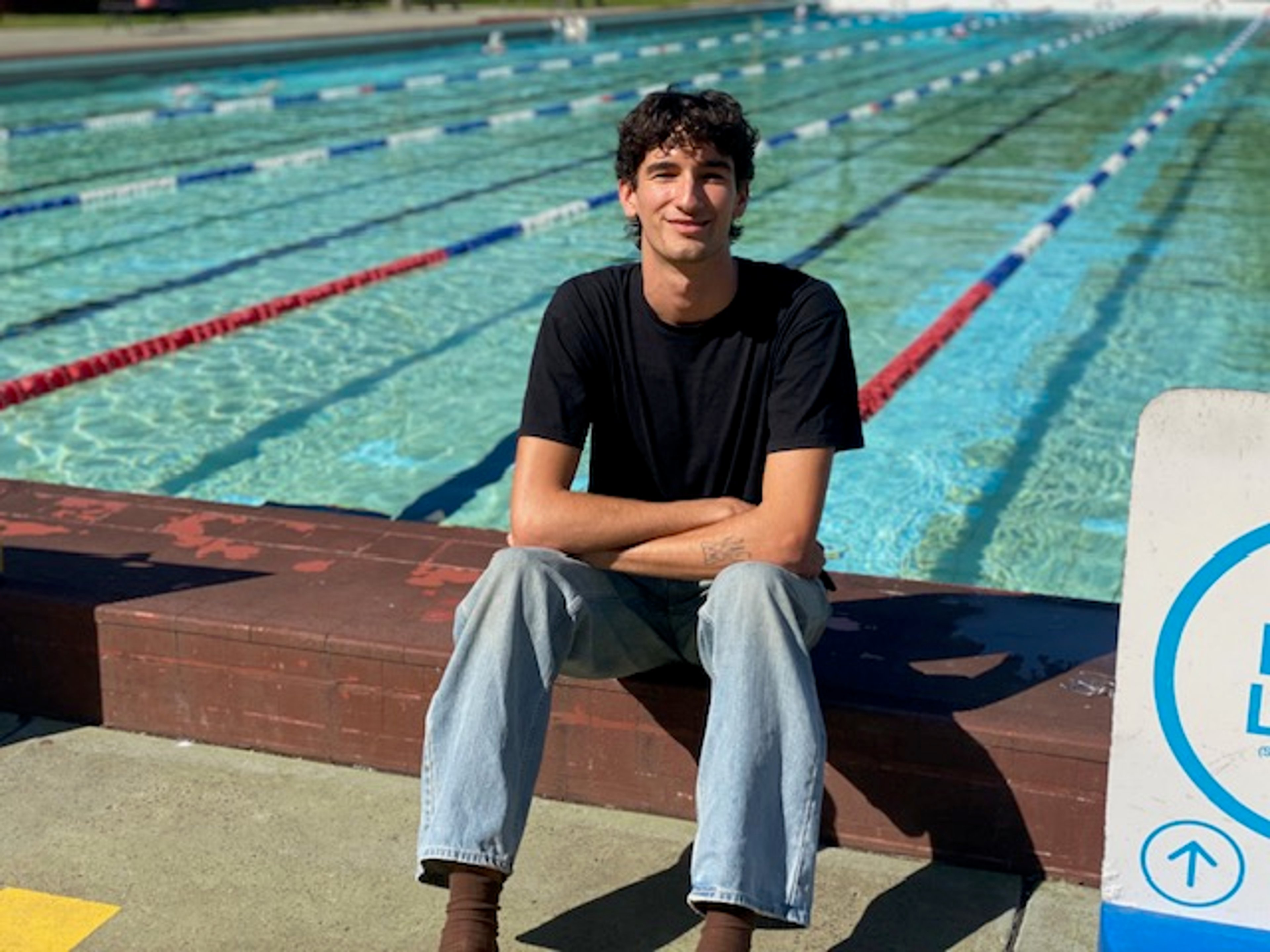 360 member Elliott sitting next to the outdoor pool at Victoria Park Pool