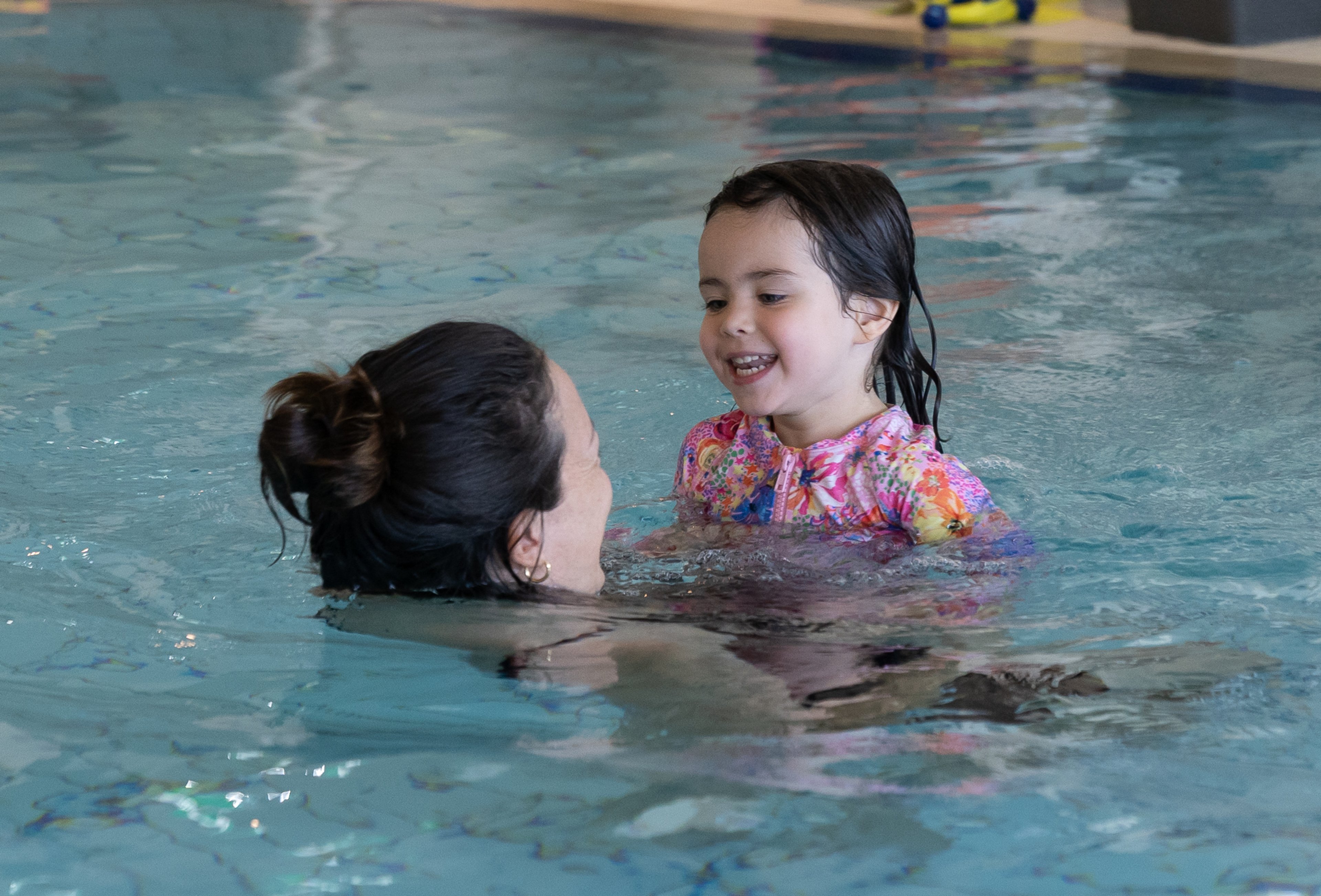 A young girl in the pool at Gunyama Park Aquatic and Recreation Centre being helped by her mother