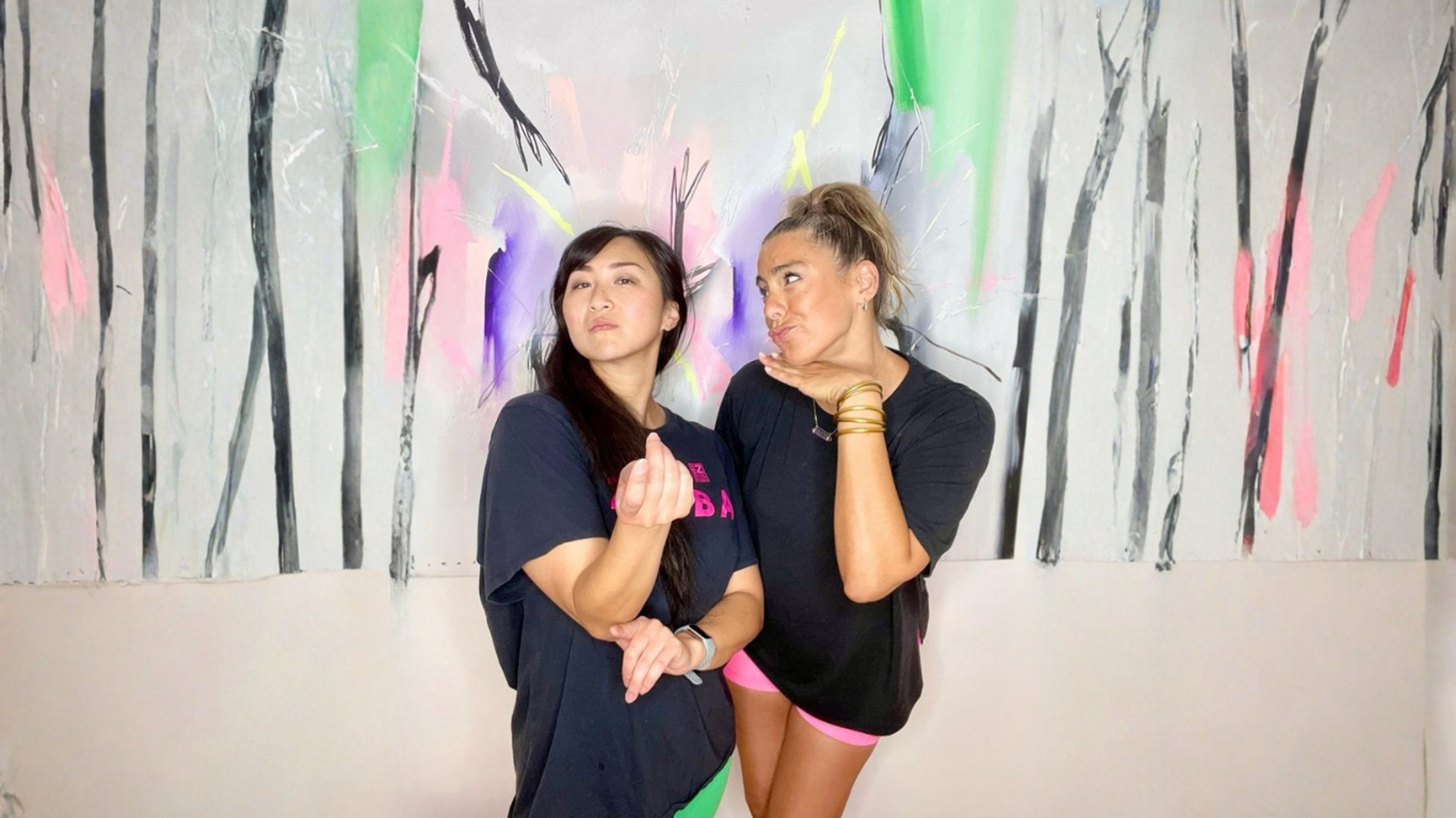Mari and Annette posing together in front of a colourful canvas