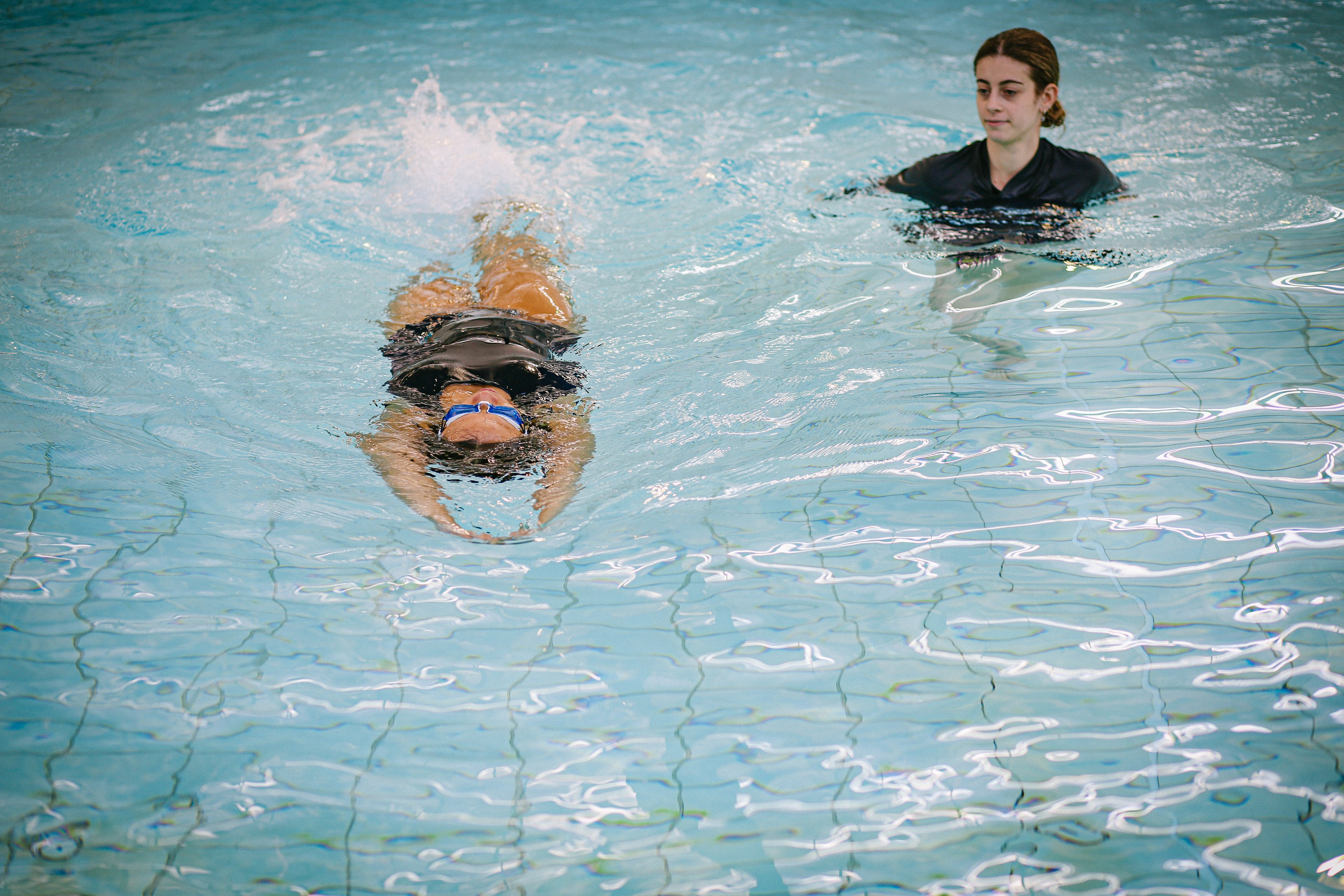 A swim teacher instructing a student at Cook + Phillip Park Pool
