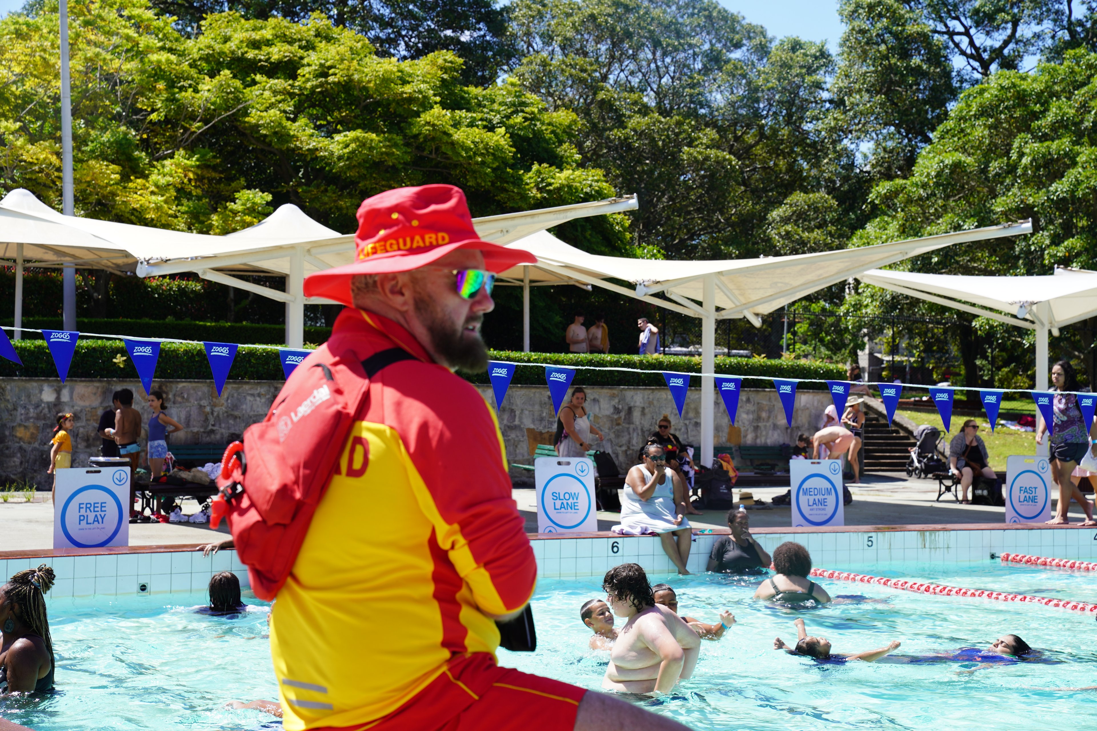 Lifeguard wearing a hat and sunglasses next to Victoria Park Pool