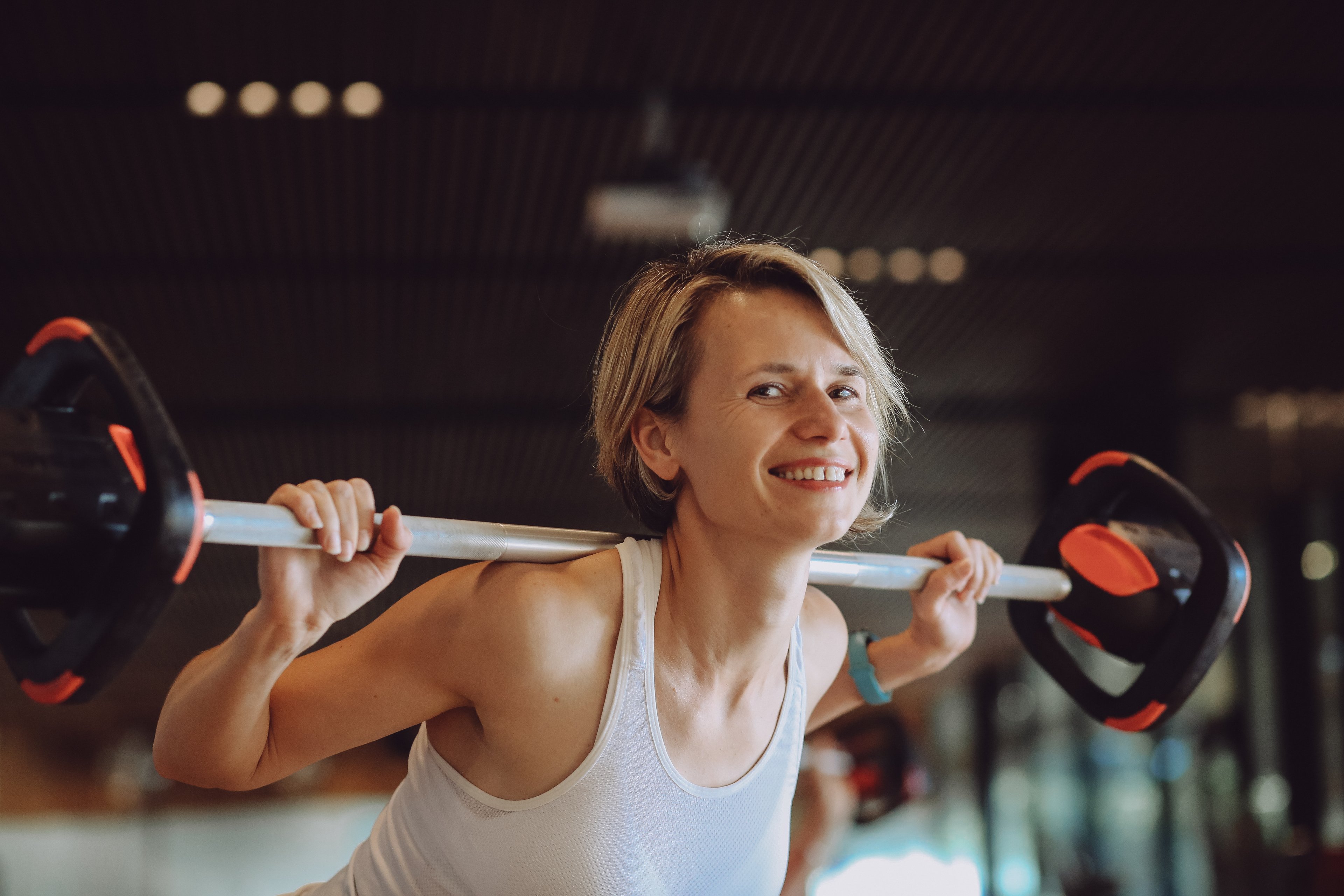 A woman smiling while lifting weights inside the gym at Gunyama Park