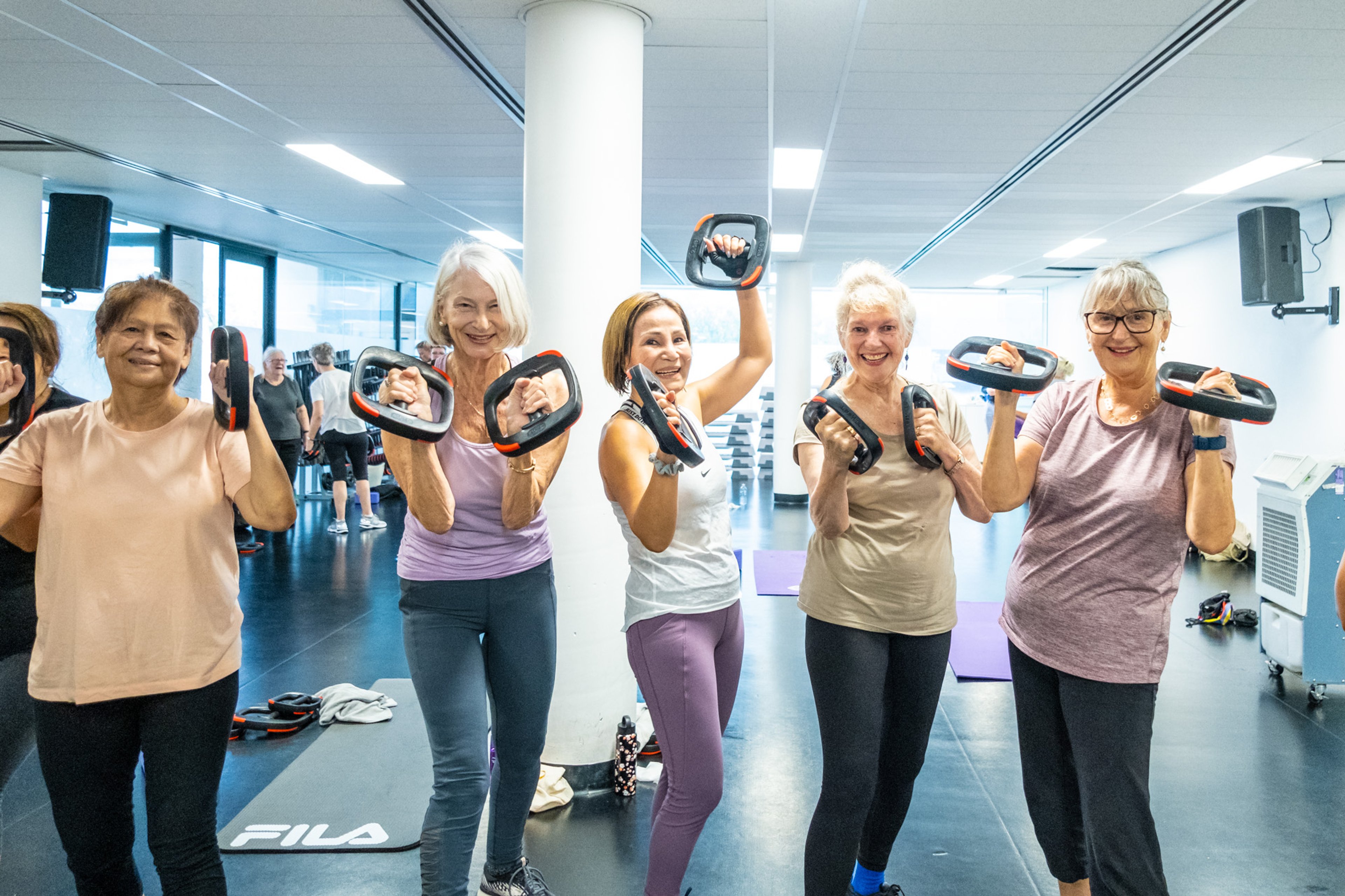 A group of GOLD members holding hand weights and smiling 