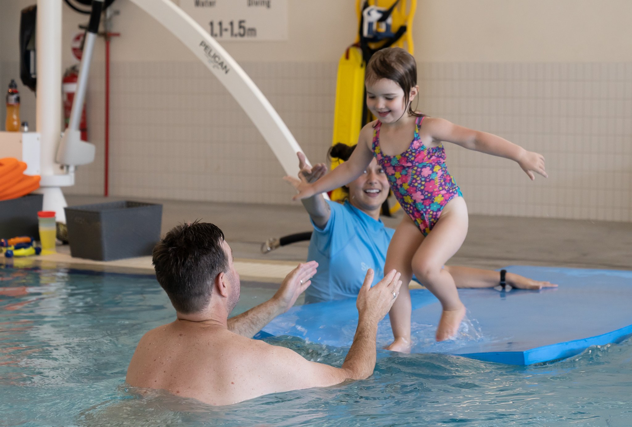 Young girl jumping towards her father during a learn to swim lesson