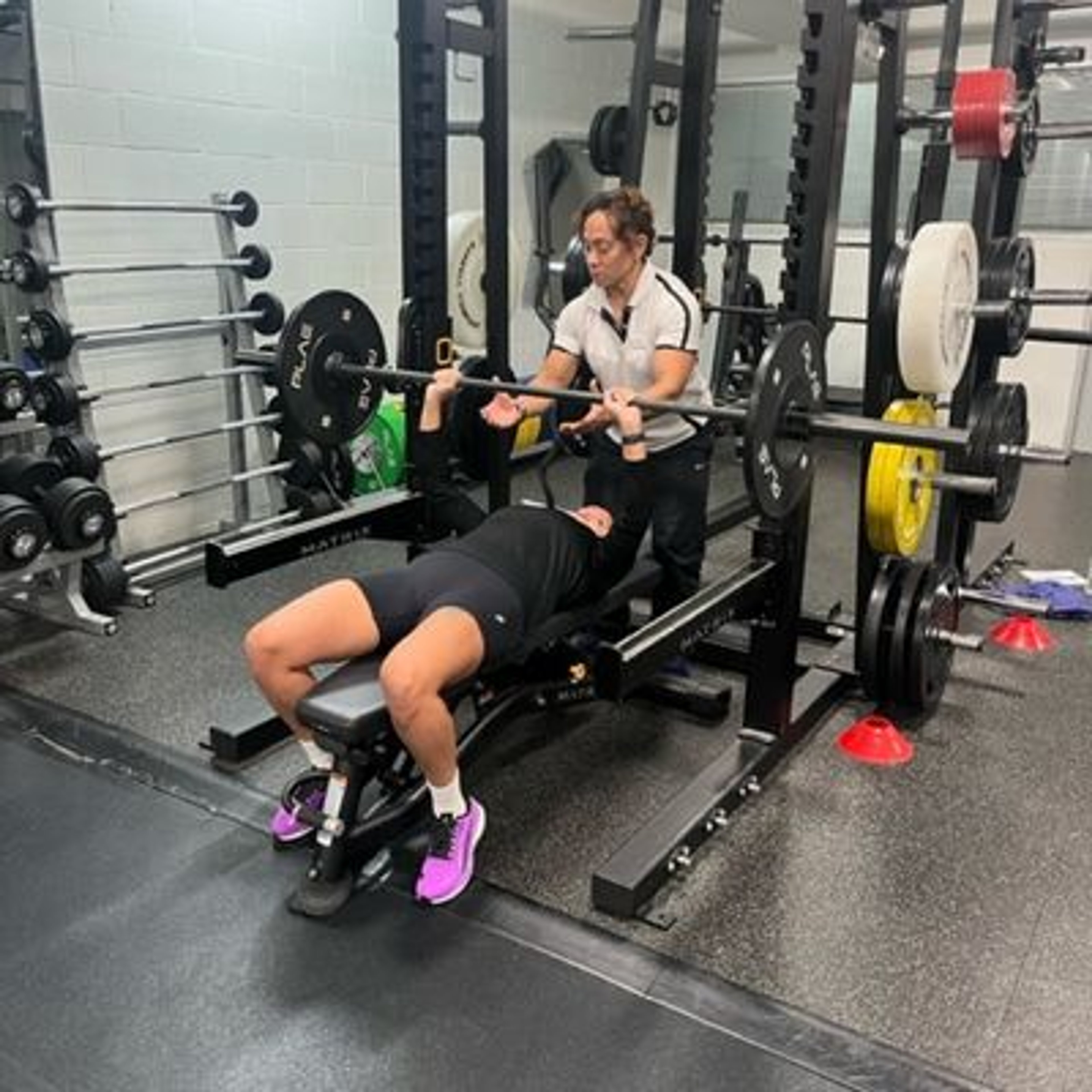 Fitness instructor Lucie assisting a client with weights 