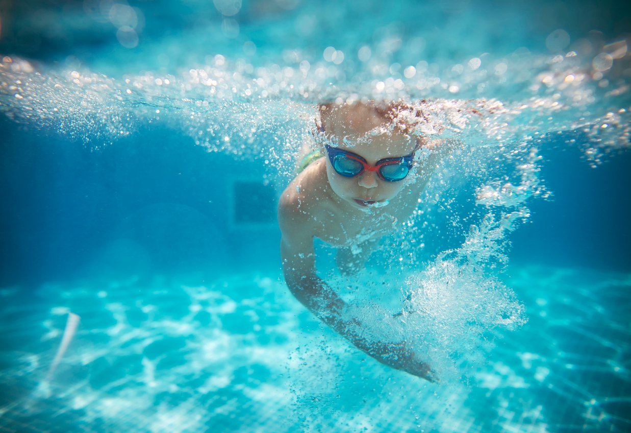 Young boy wearing goggles and swimming underwater
