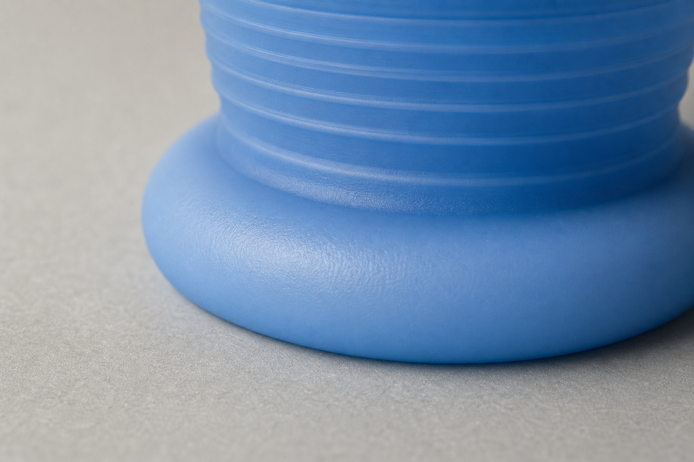 Macro shot of a printed silicone plug compressed under load, bulging at its waist with light glowing through its edges