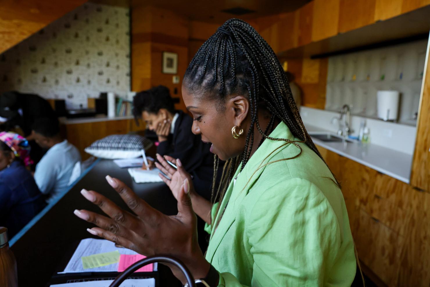 A woman leaning over documents, hands gesturing, as if in conversation.