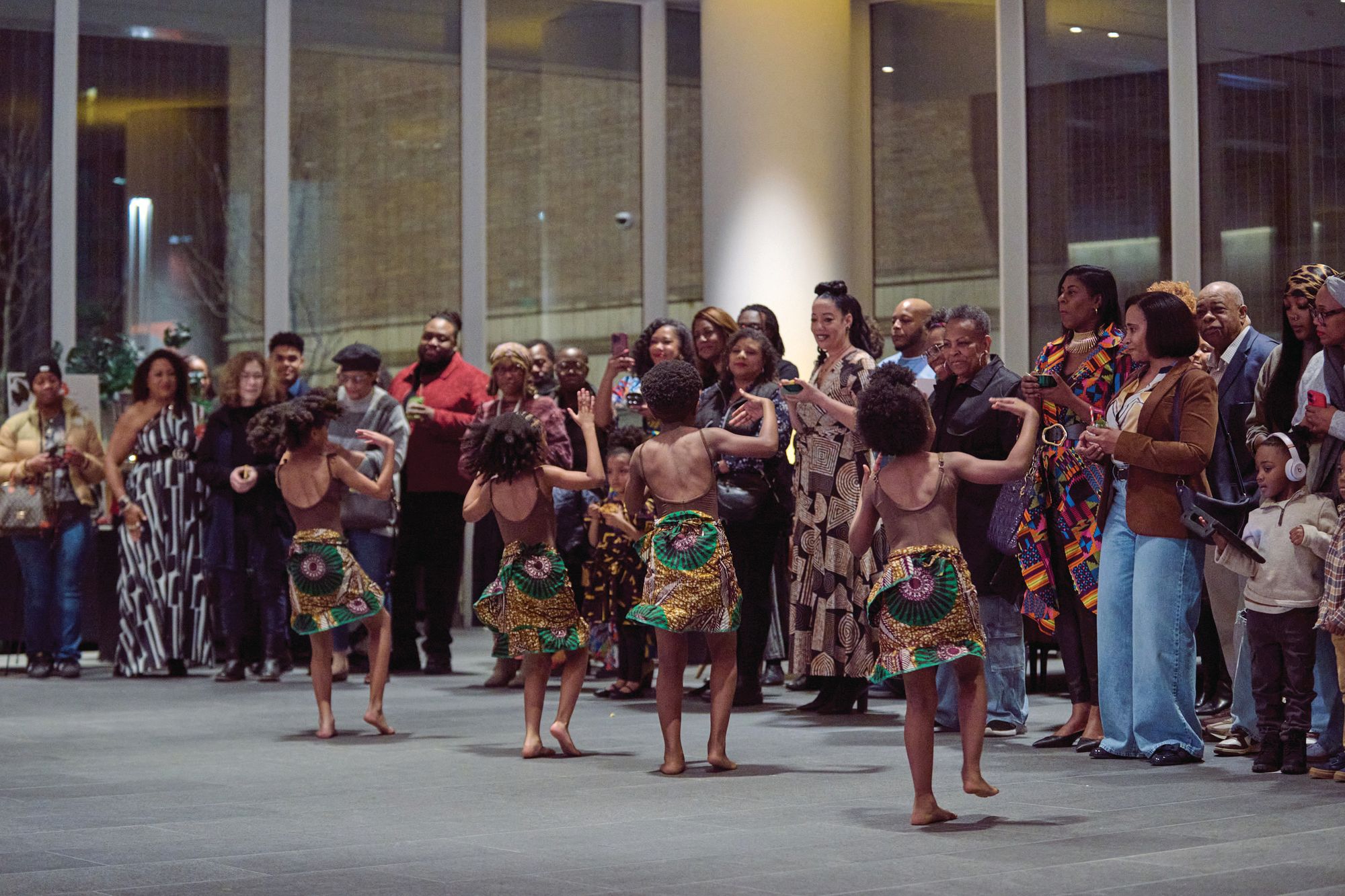 Four young people dancing in front of a crowd of onlookers