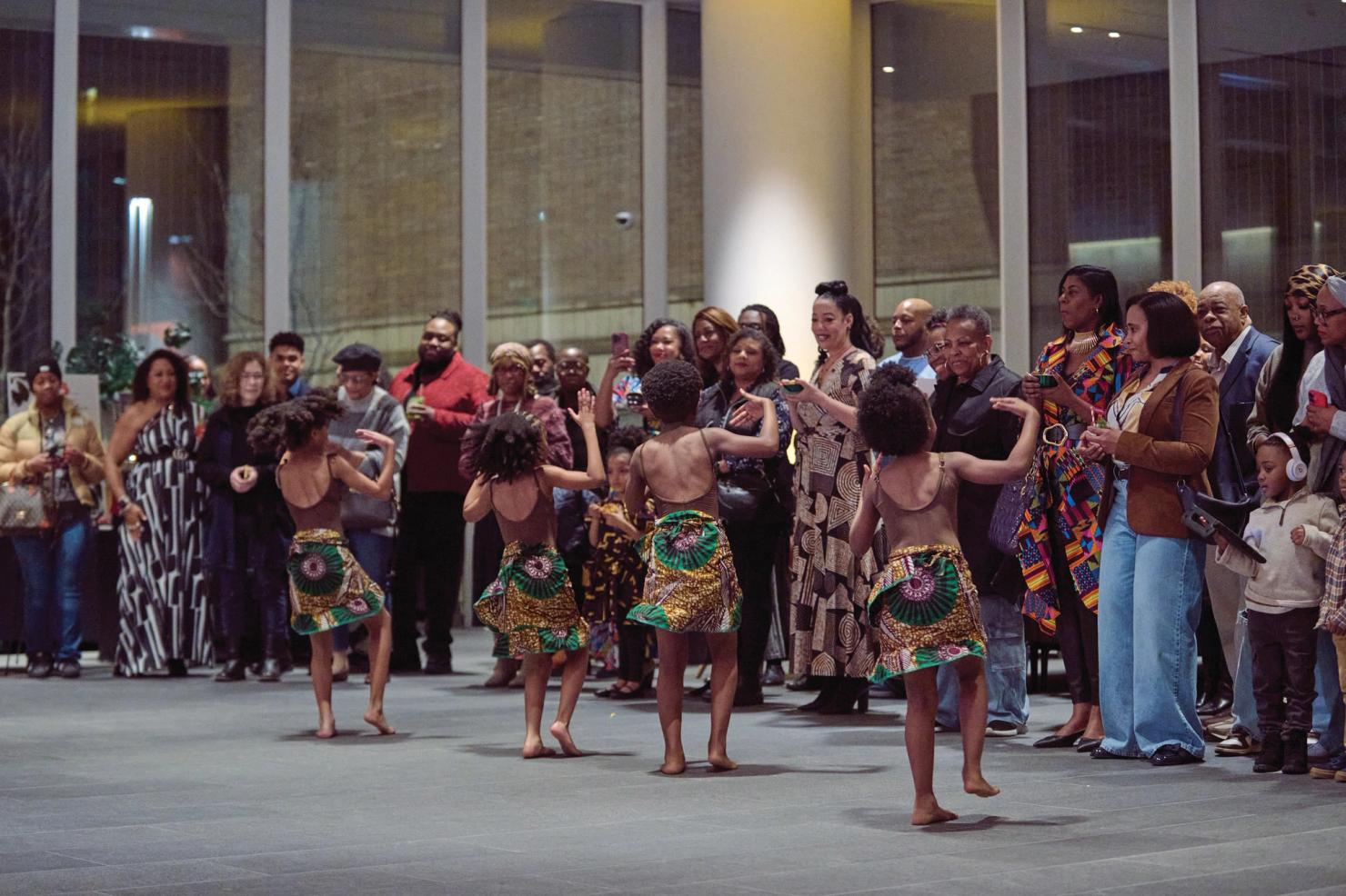 Four young people dancing in front of a crowd of onlookers