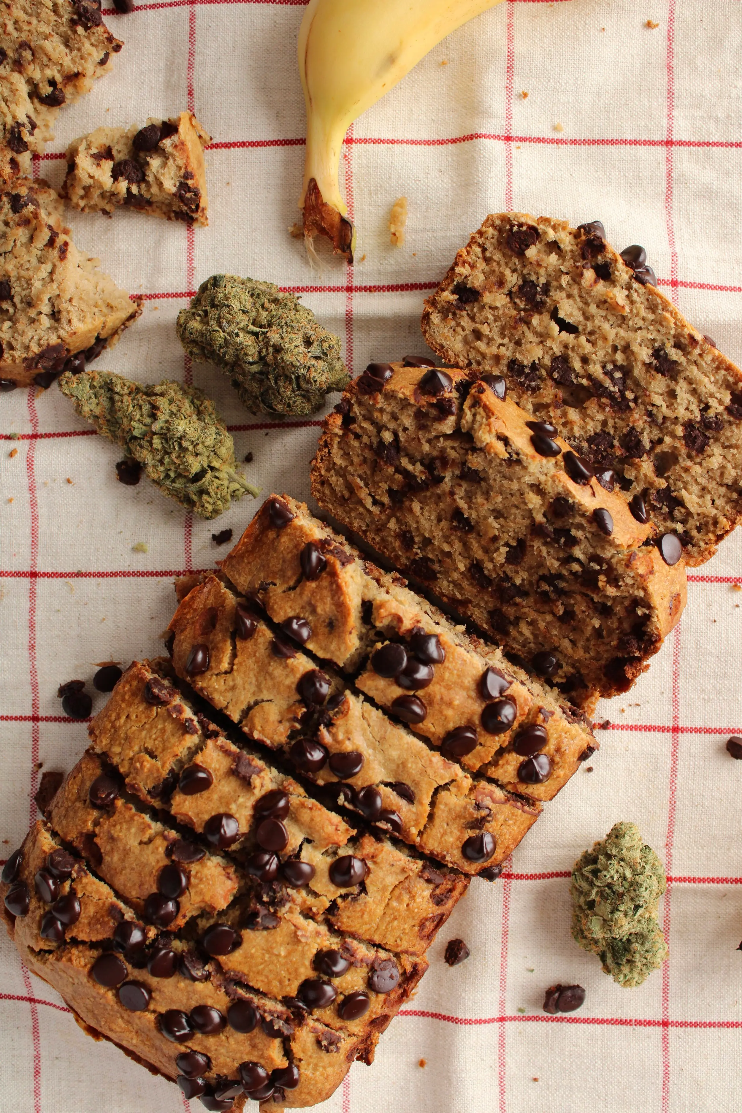 an aerial shot of a loaf of banana bread which is cut up into a few pieces. The banana bread is topped with chocolate chips.