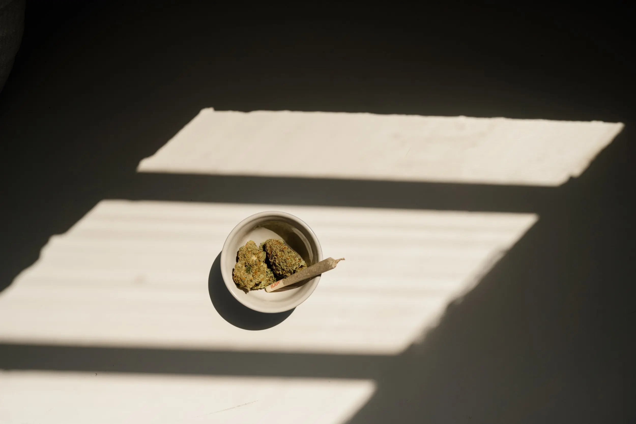 an aerial shot of two nuggets of cannabis in a granite coloured dish, with a joint sticking out of it.