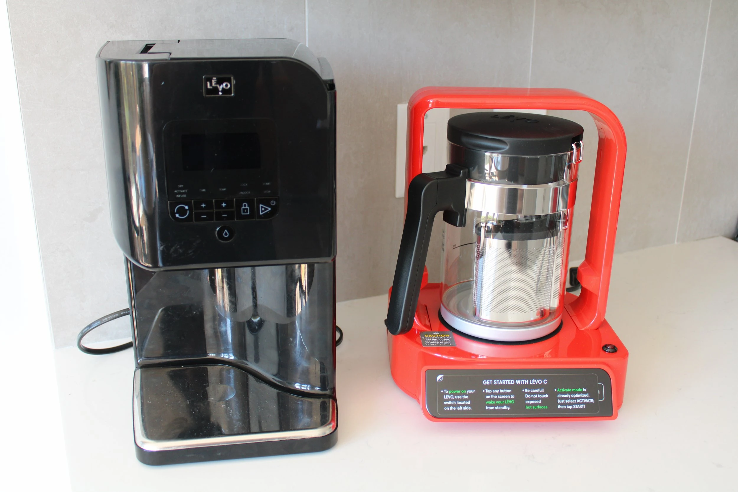 Two large LEVO diffusion devices sitting on a white marble countertop next to each other.