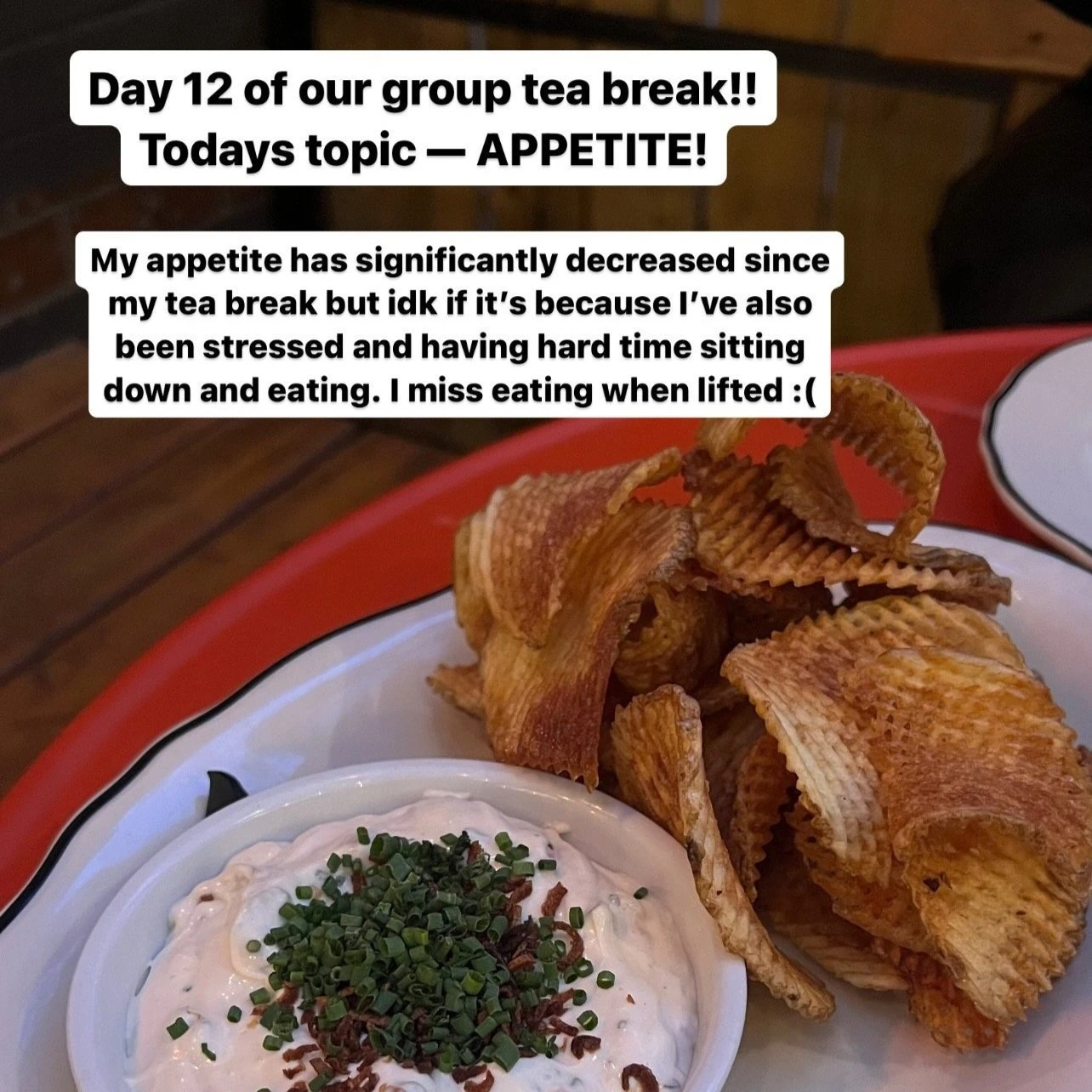 A red plate with chips and a dip on top of it, with text that reads "Day 12 of our group tea break!! Today's topic - appetite! My appetite has significantly decreased since my tea break but idk if it's because I've also been stressed and having a hard time sitting down an eating. I miss eating when lifted :("