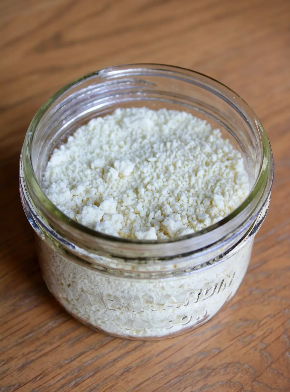 a small mason jar of white powder sitting on a light wood table.