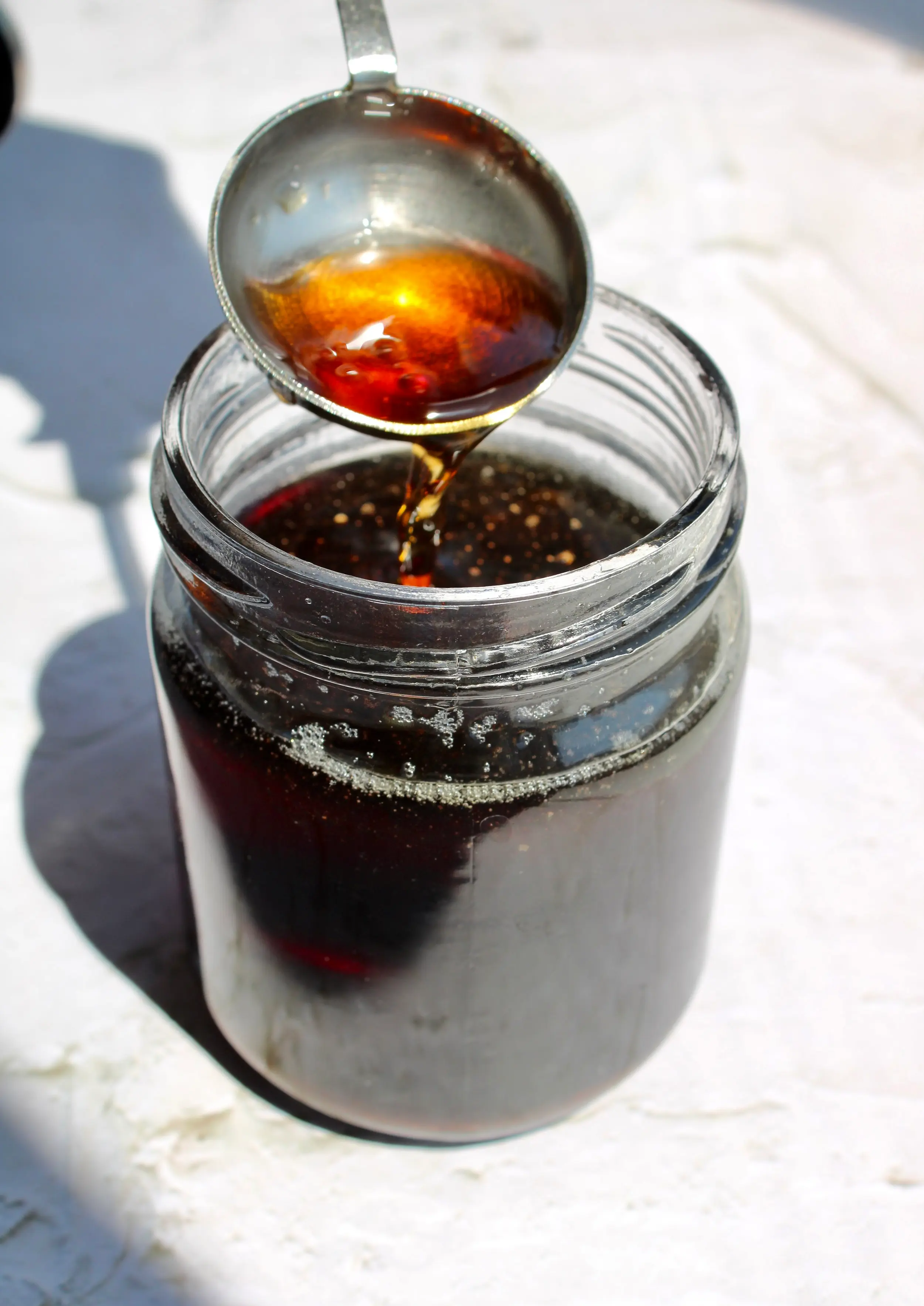 a large jar of infused maple syrup with a spoon coming out the top, dripping with maple syrup.