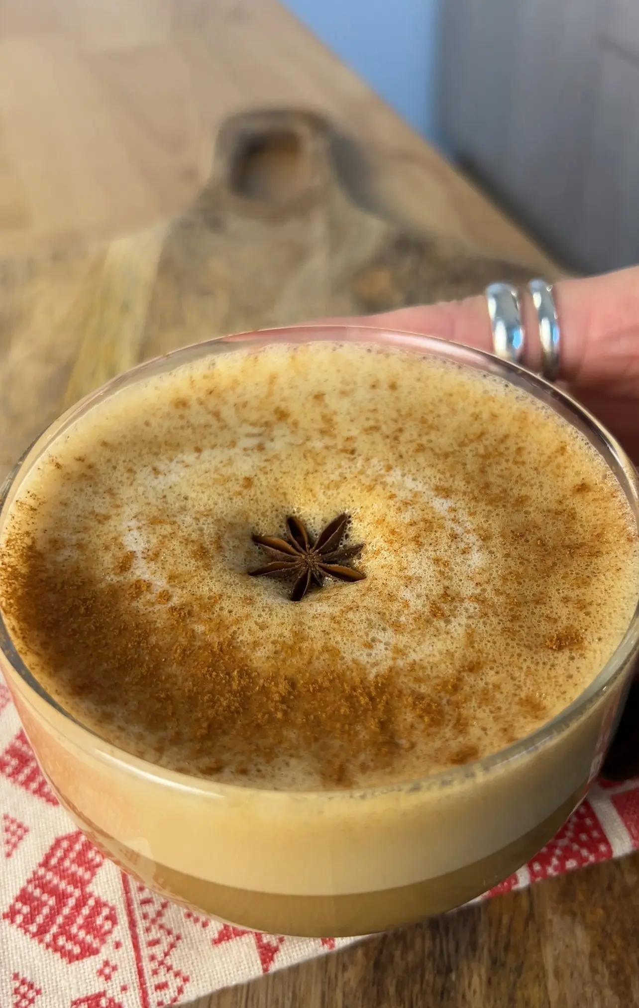 An aerial shot of a glass mug full with an eggnog latte and garnished with star anise and cinnamon.