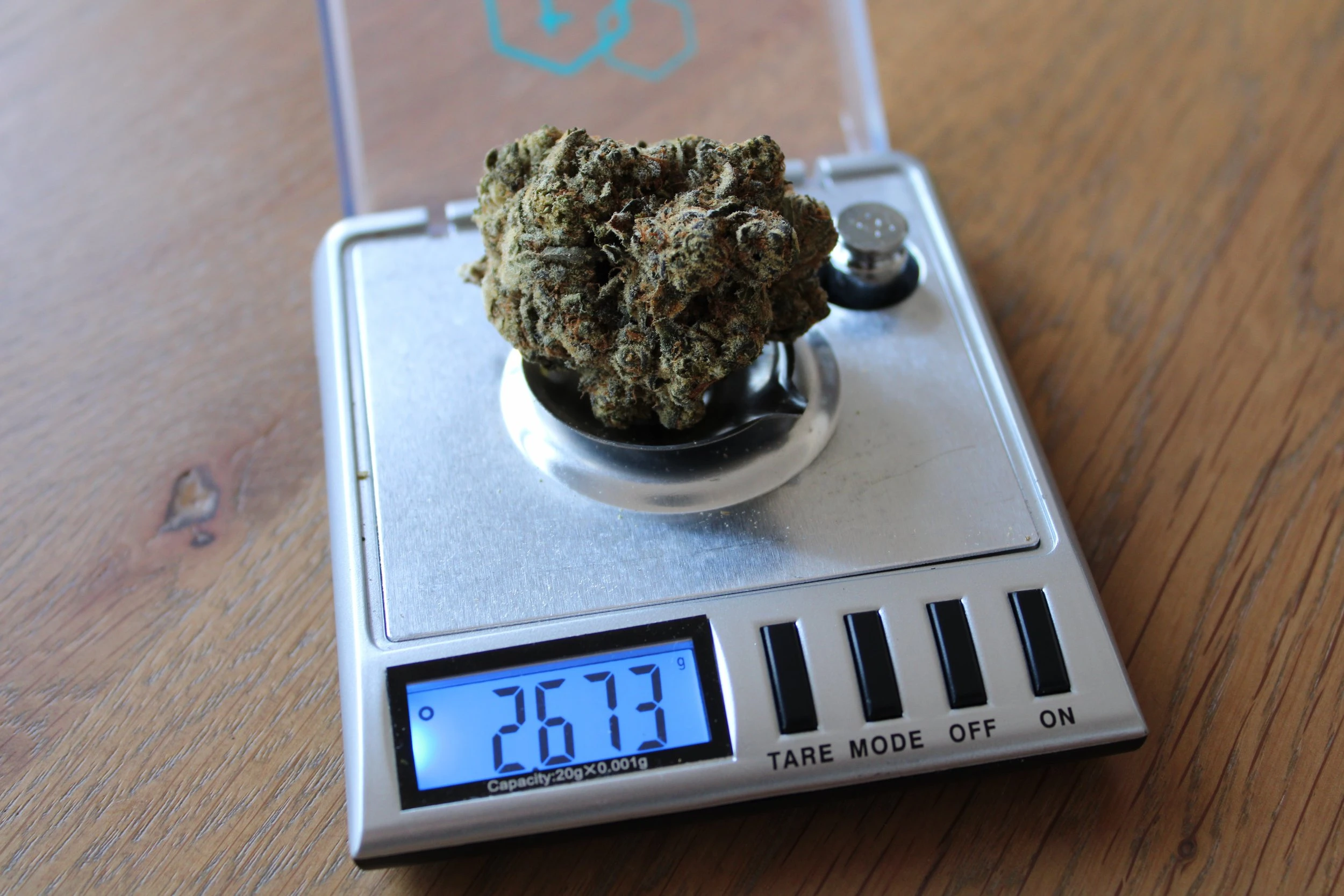 A large cannabis nugget on a silver metal scale which reads 2673 on the electronic screen.