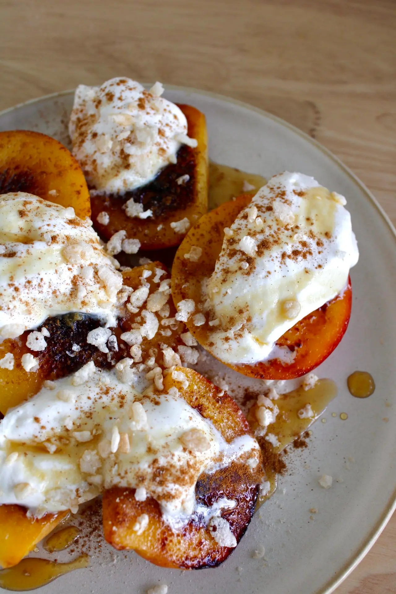 A cream plate of halved peaches with small dollops of whipped cream on top of them.