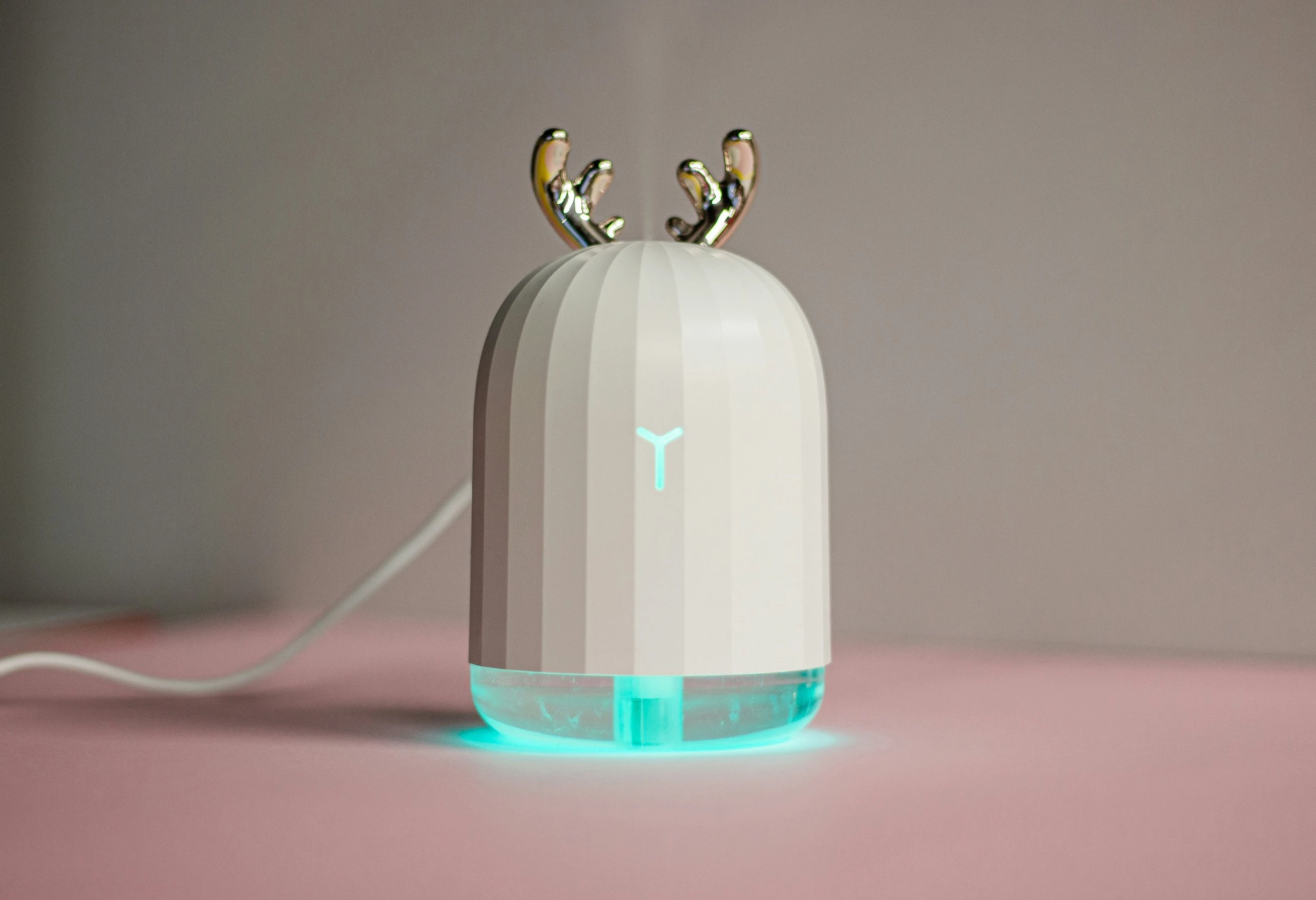 A white humidifier with gold antlers and a light blue neon ring around the bottom.