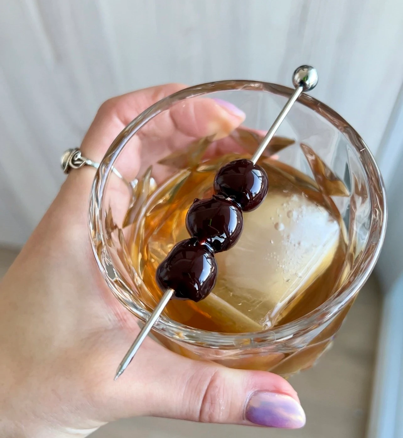 A hand holding a rocks glass full of a cannabis infused old fashioned.