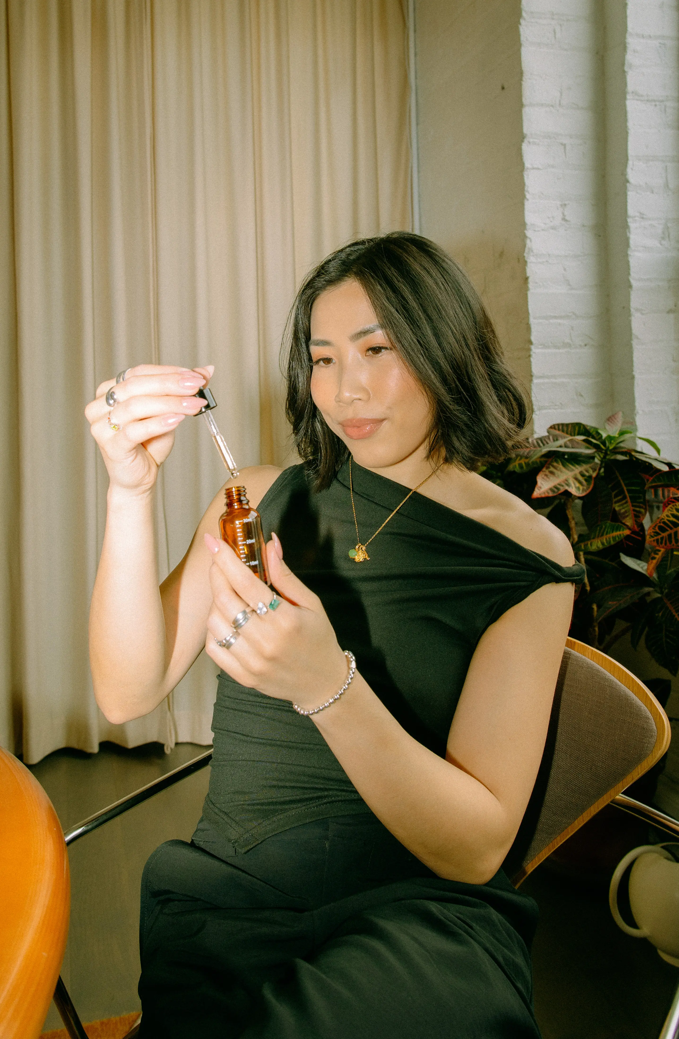 Anna The Cannabinista (a woman with short brown hair tied back) is holding a cannabis oil tincture bottle.