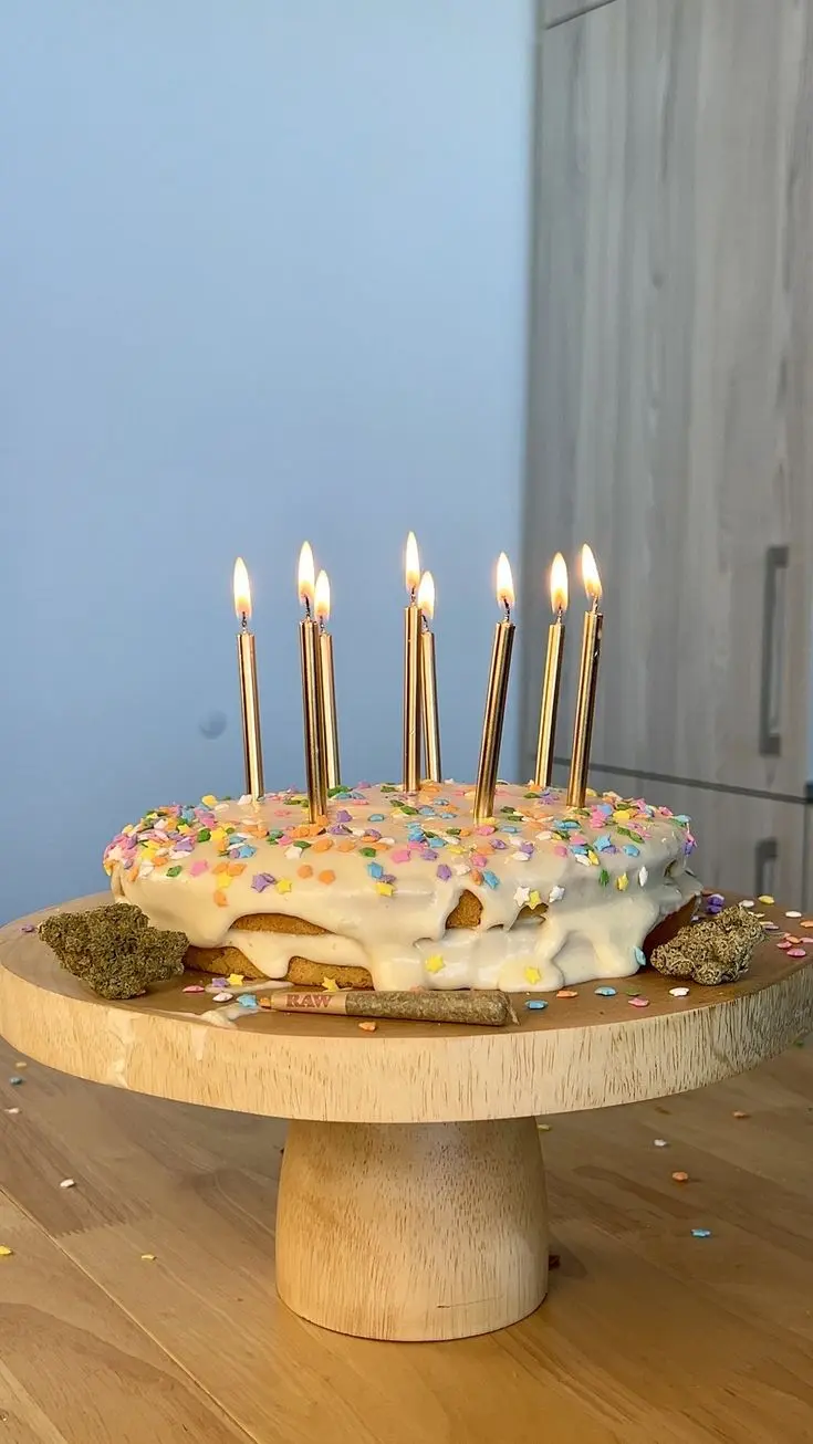 Weed birthday came with gold, lit candles on top of white goopy frosting which is covered by multicoloured sprinkles. 