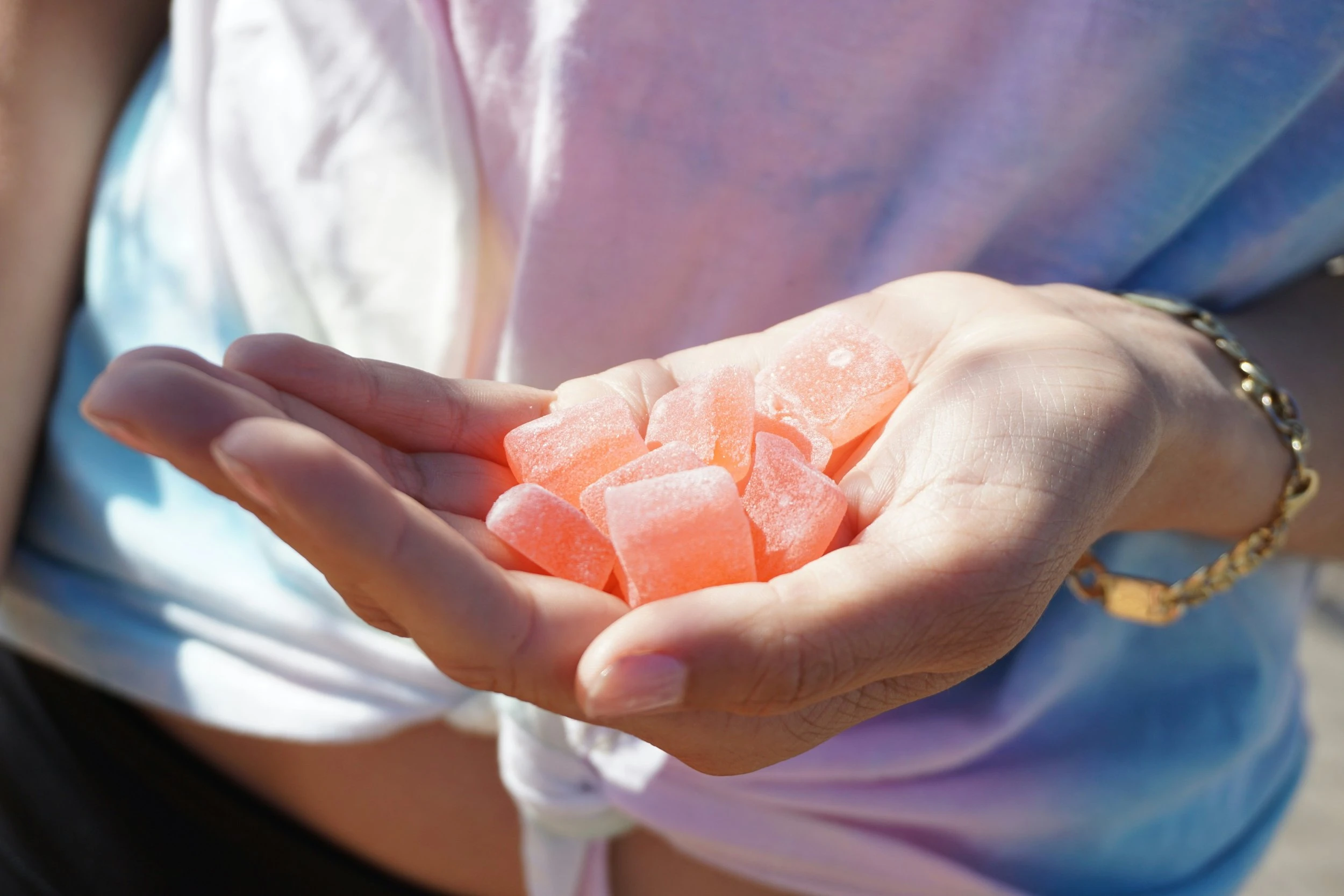 A hand holding a large handful of pink gummies.