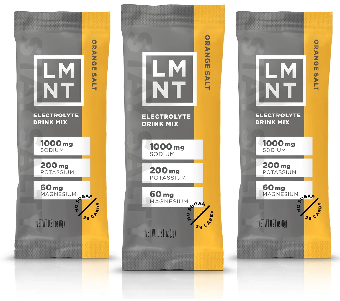 Three yellow and grey packs of LMNT branded dissolvable electrolytes rest in a line next to each other.