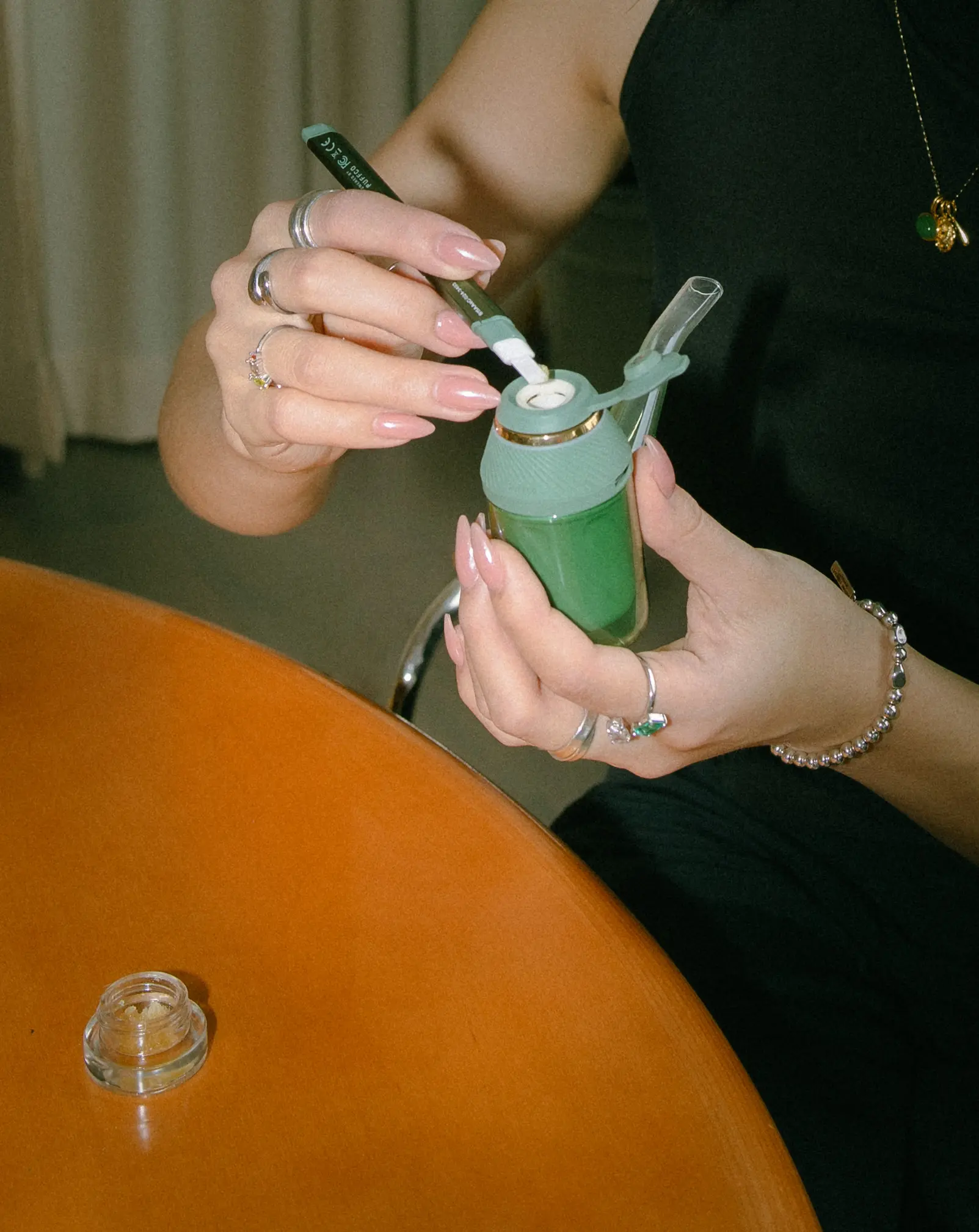 Anna The Cannabinista (A woman with dark brown hair tied back) holding up a joint in one hand and a PAX vaporizer in the other. The title text above her head reads Vaporizing vs. Smoking Cannabis.