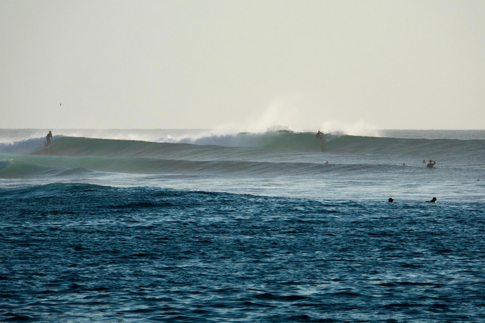 Surfers riding waves at Nemberala on Rote Island, East Nusa Tenggara, Indonesia