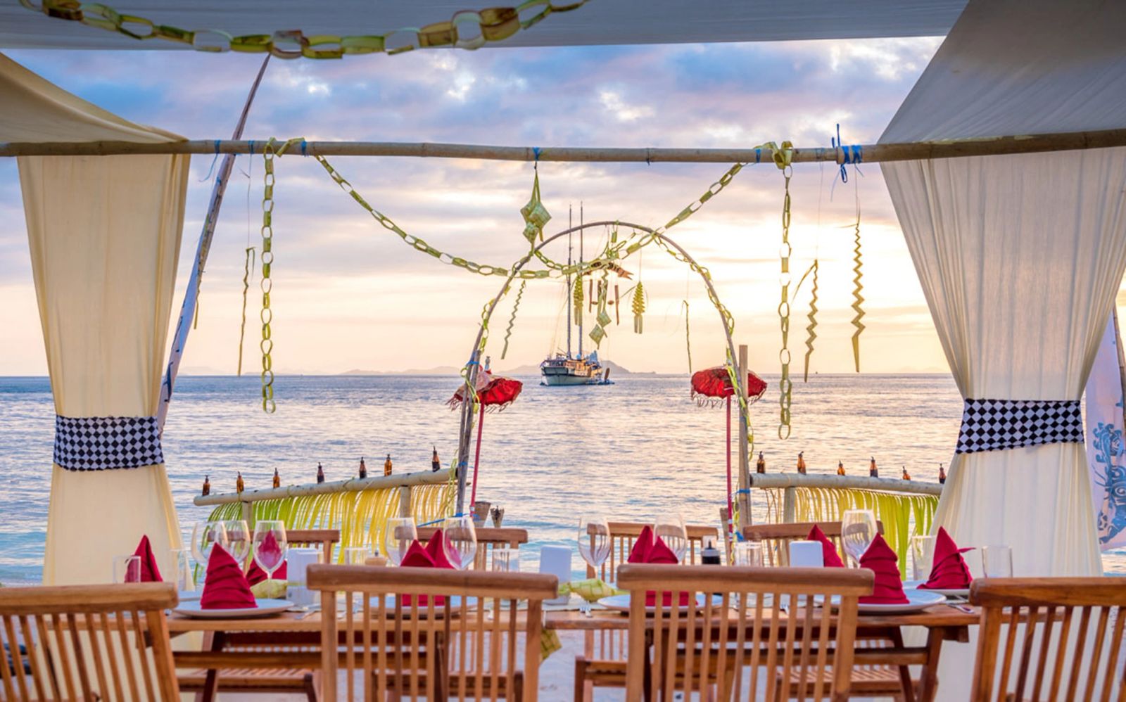 A holiday dinner table on deck, dressed with garlands at sunset