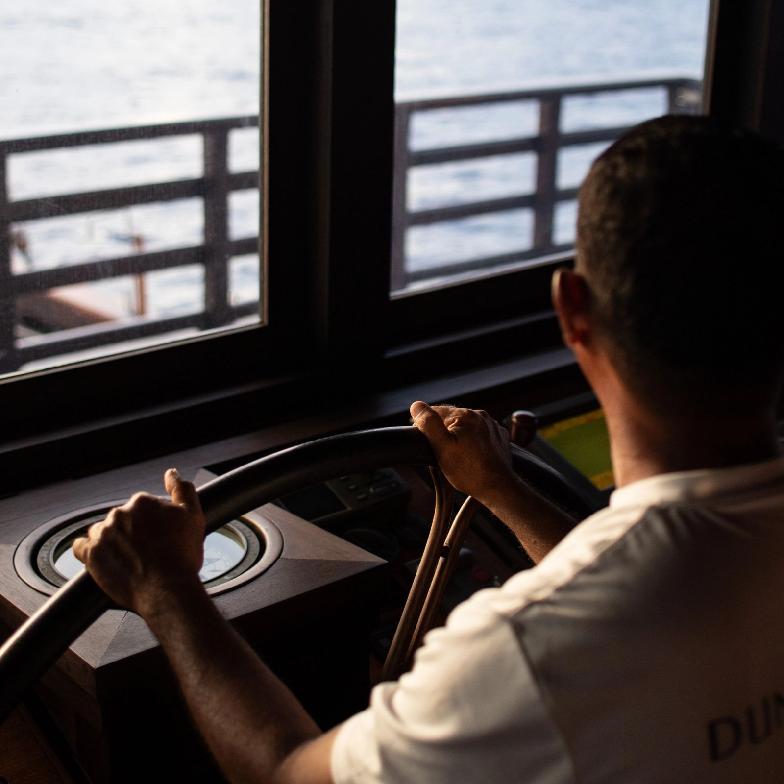 Dunia Baru's helmsman at the wheel, the compass beside his hands