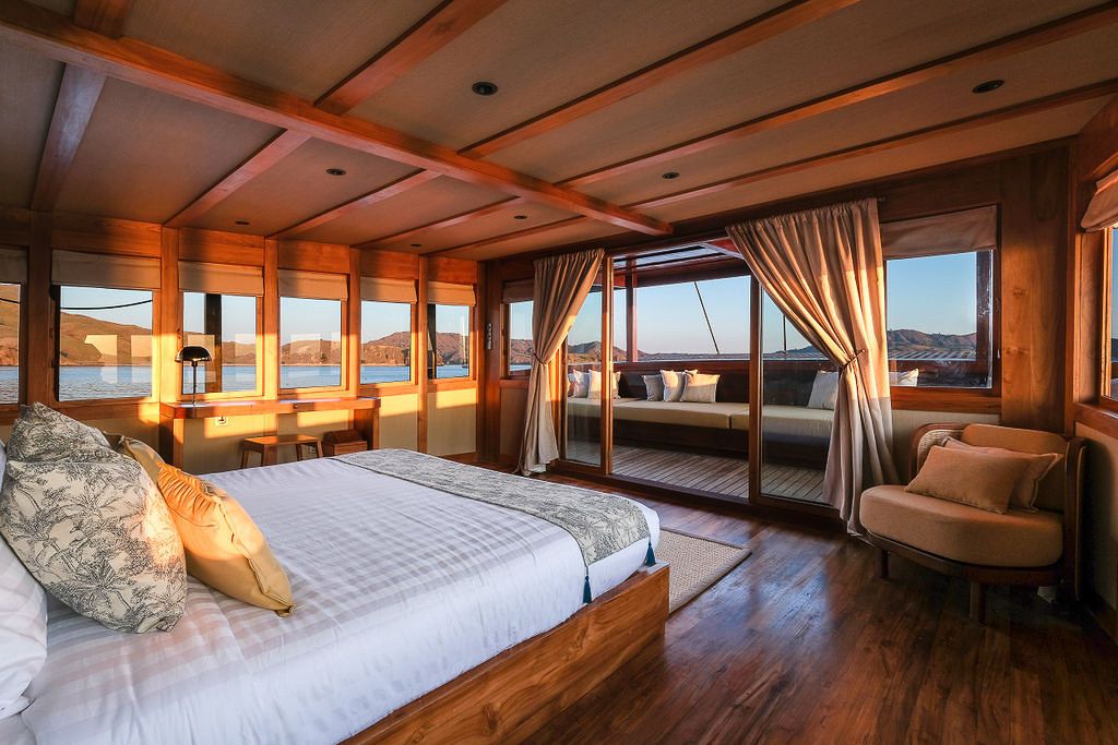 The master stateroom on Celestia with curtains and a sitting chair at sunset.