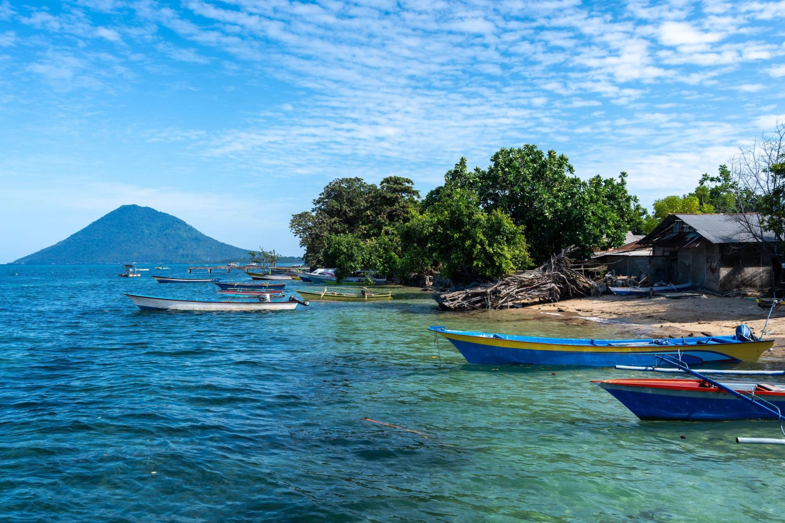 A fishing harbor on Bunaken Island with Manado Tua rising across the water.