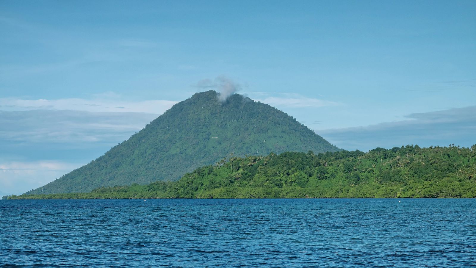 A volcanic cone rising straight from open water, the signature of the Banda Sea arc.
