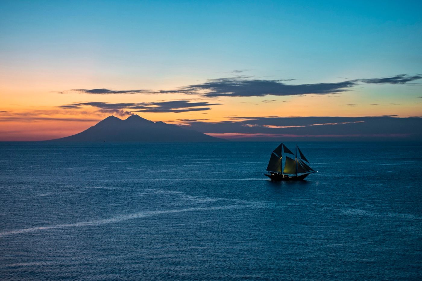 A phinisi silhouette at dusk off the Komodo hills