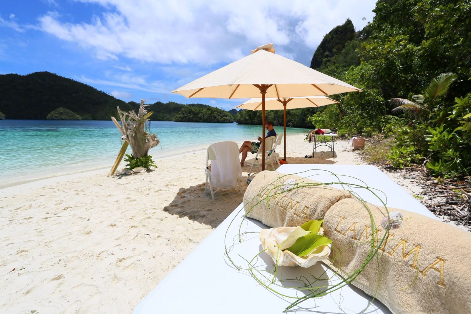A beach set for lunch under parasols among the islands of Raja Ampat
