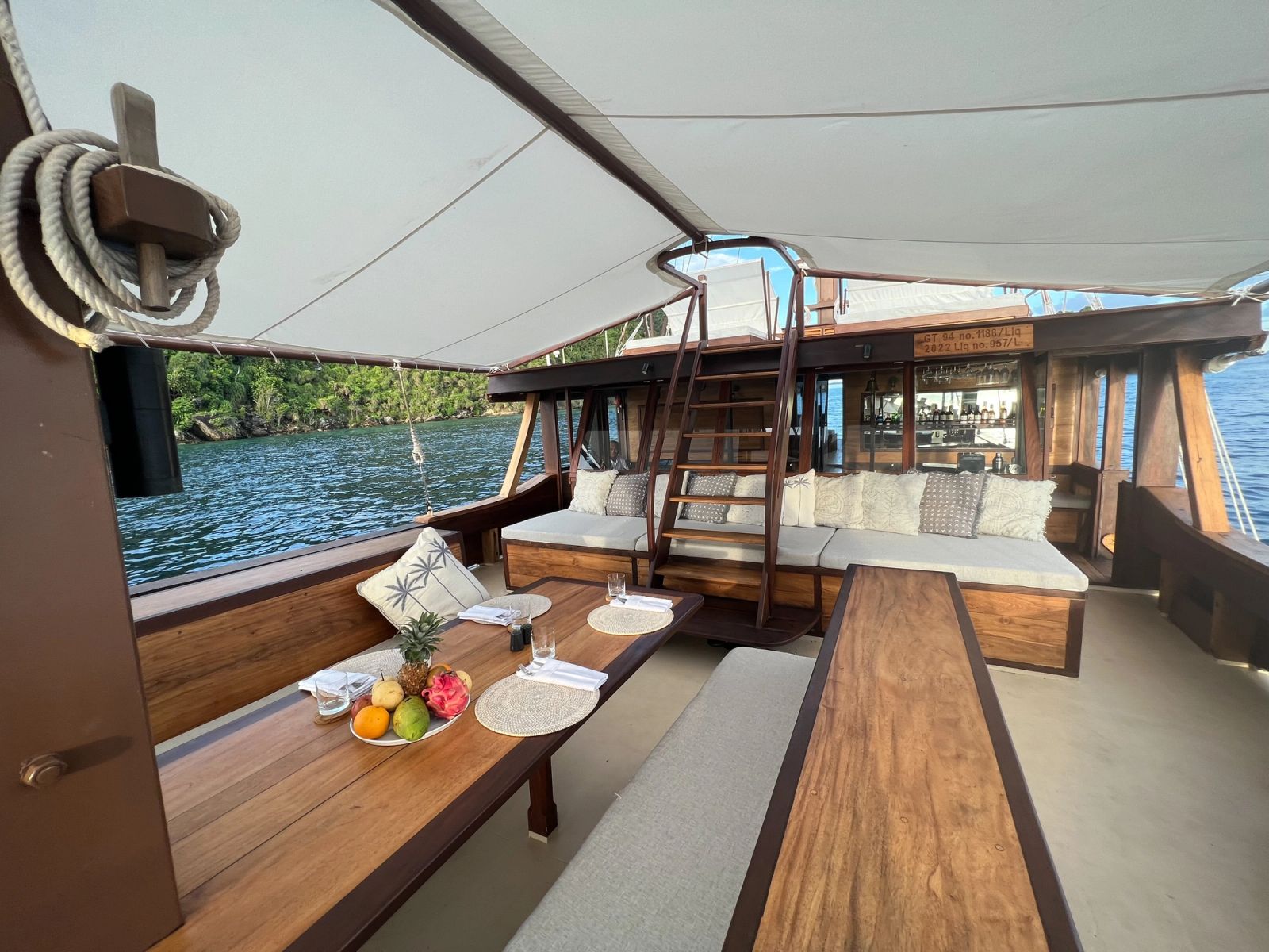 A breakfast table on the foredeck of Dewata with a bowl of fruit and cups.