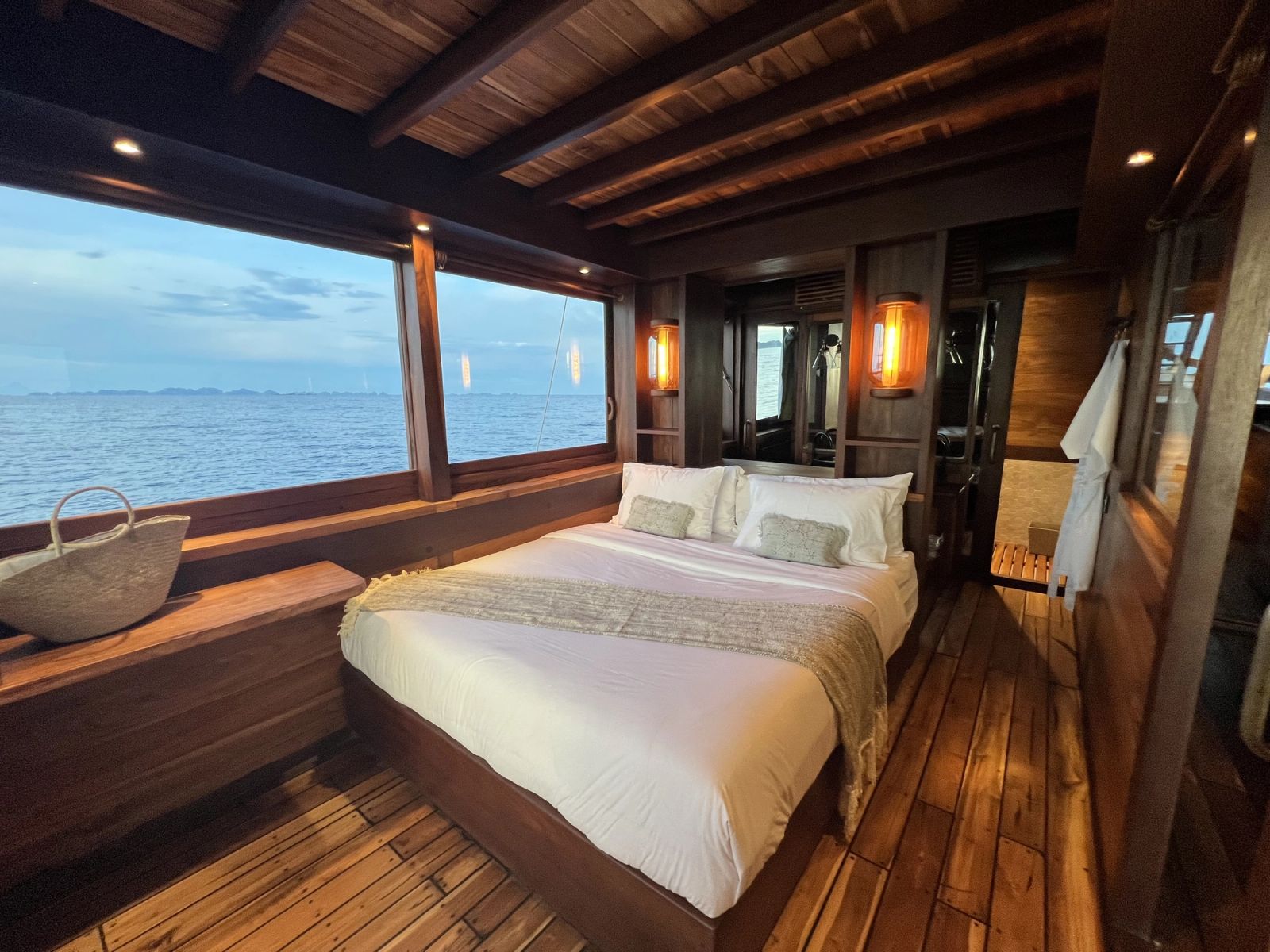 The master cabin on Dewata at night with a bed beneath wide windows.
