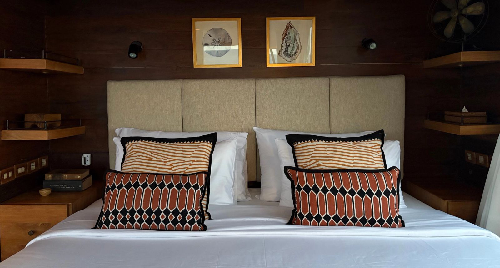 A bed with patterned cushions and a cream headboard in the master cabin on El Aleph.