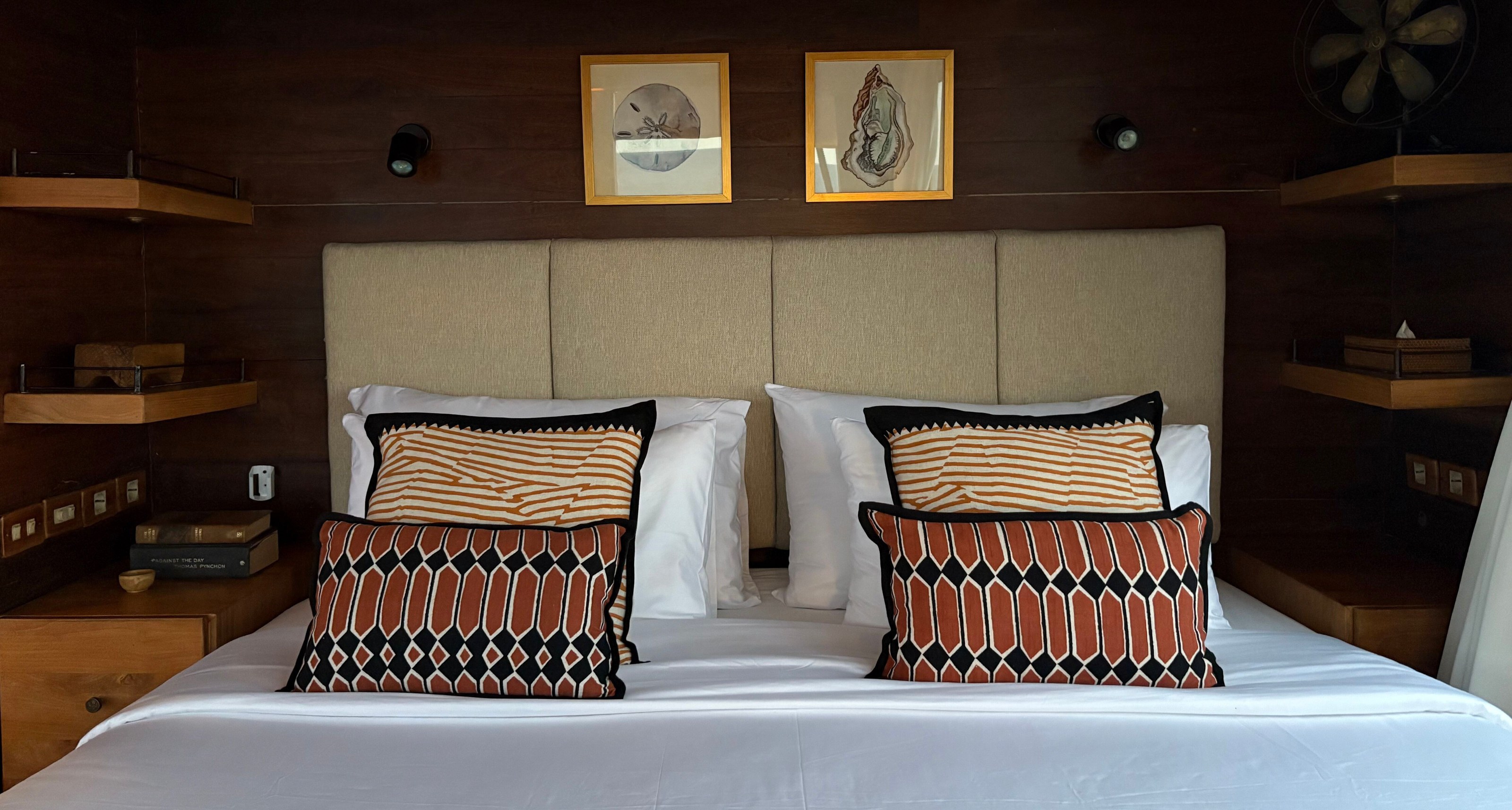 A bed with patterned cushions and a cream headboard in the master cabin on El Aleph.