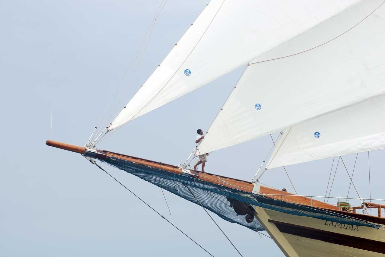 A crew member stands on the bowsprit of the phinisi Lamima under full sail
