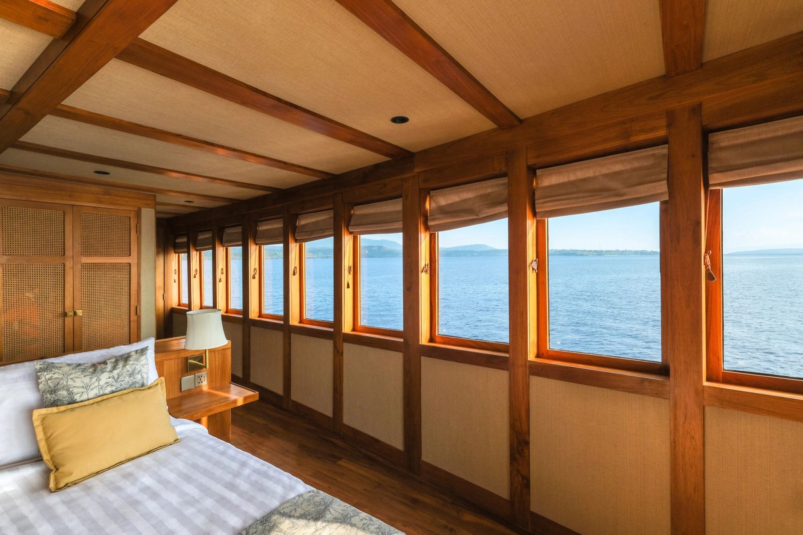 The owner's stateroom on Celestia with a bed beside a row of windows.