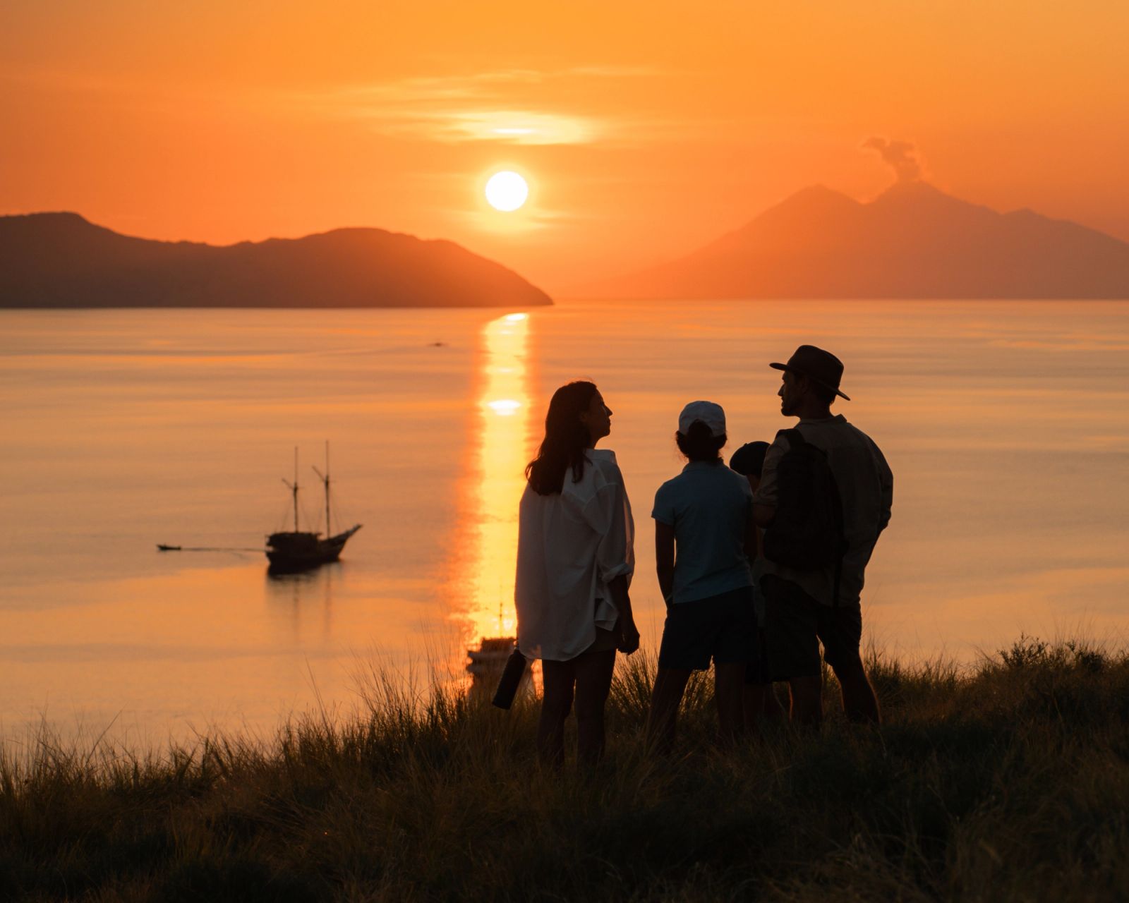 Guests watching the sun set from a grassy hilltop