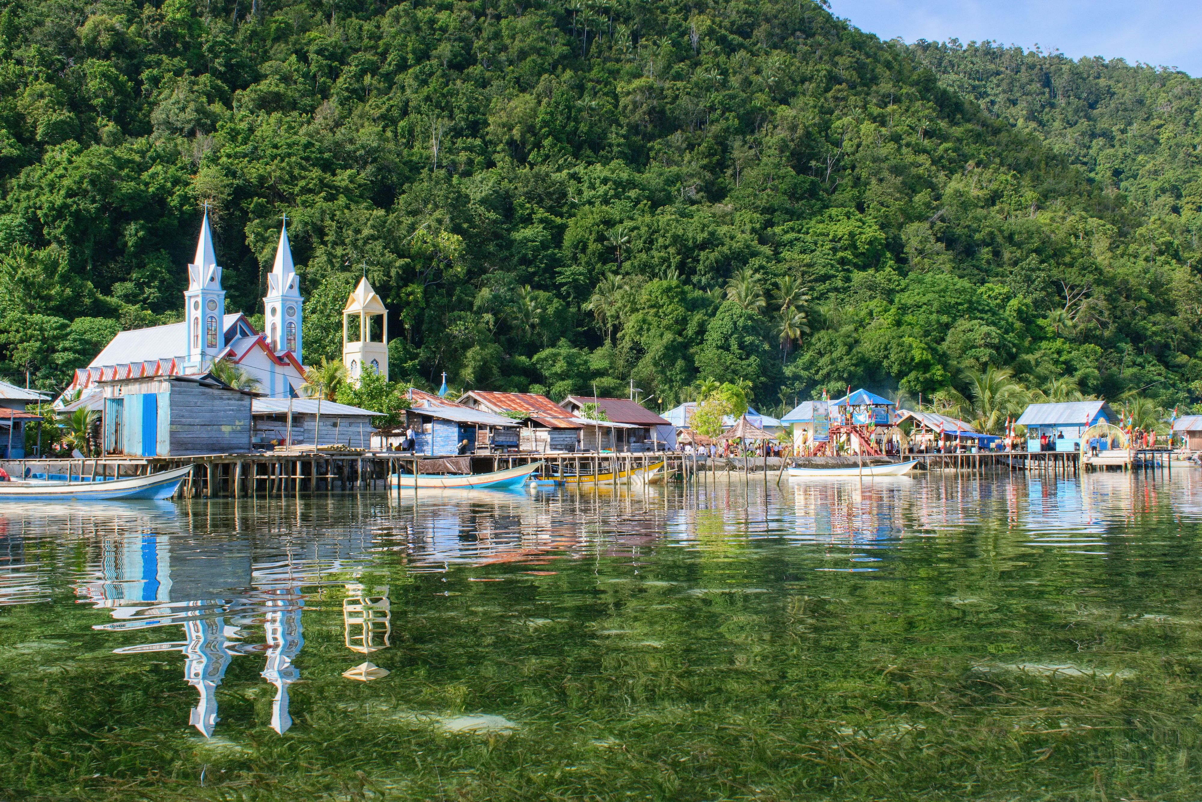 A village with a white church on the water in Raja Ampat